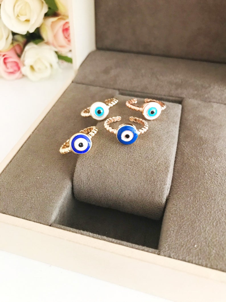 Adjustable evil eye ring featuring blue and white beads on a gold band, symbolizing protection and style.