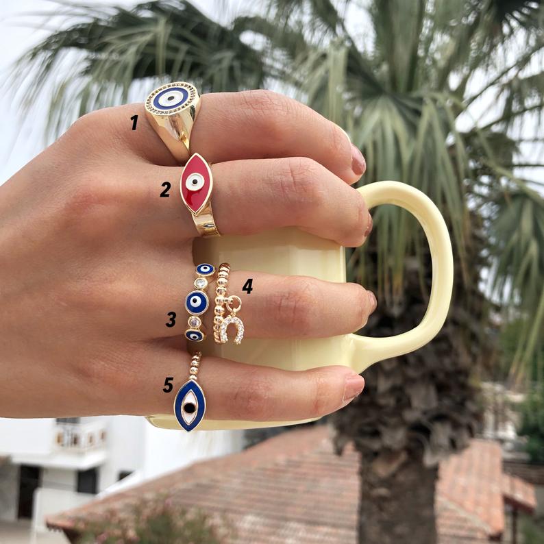 A collection of adjustable gold rings featuring various evil eye designs, showcasing their unique styles and charm.