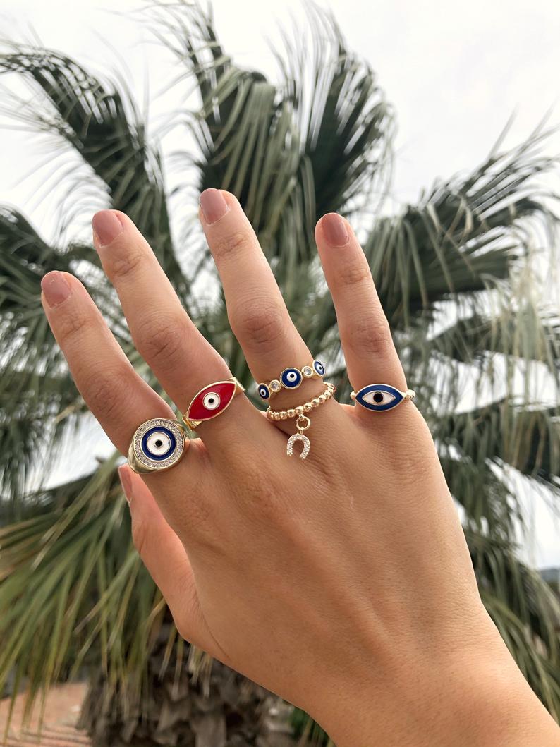 A collection of adjustable gold rings featuring various evil eye designs, showcasing their unique styles and charm.