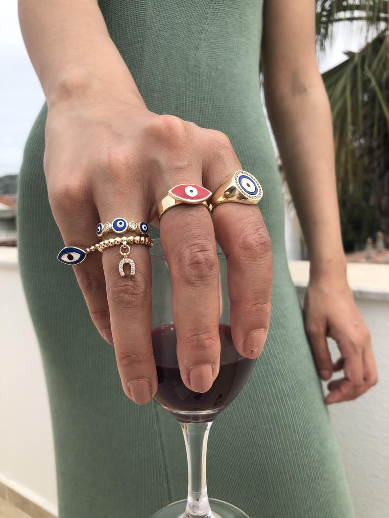 A collection of adjustable gold rings featuring various evil eye designs, showcasing their unique styles and charm.