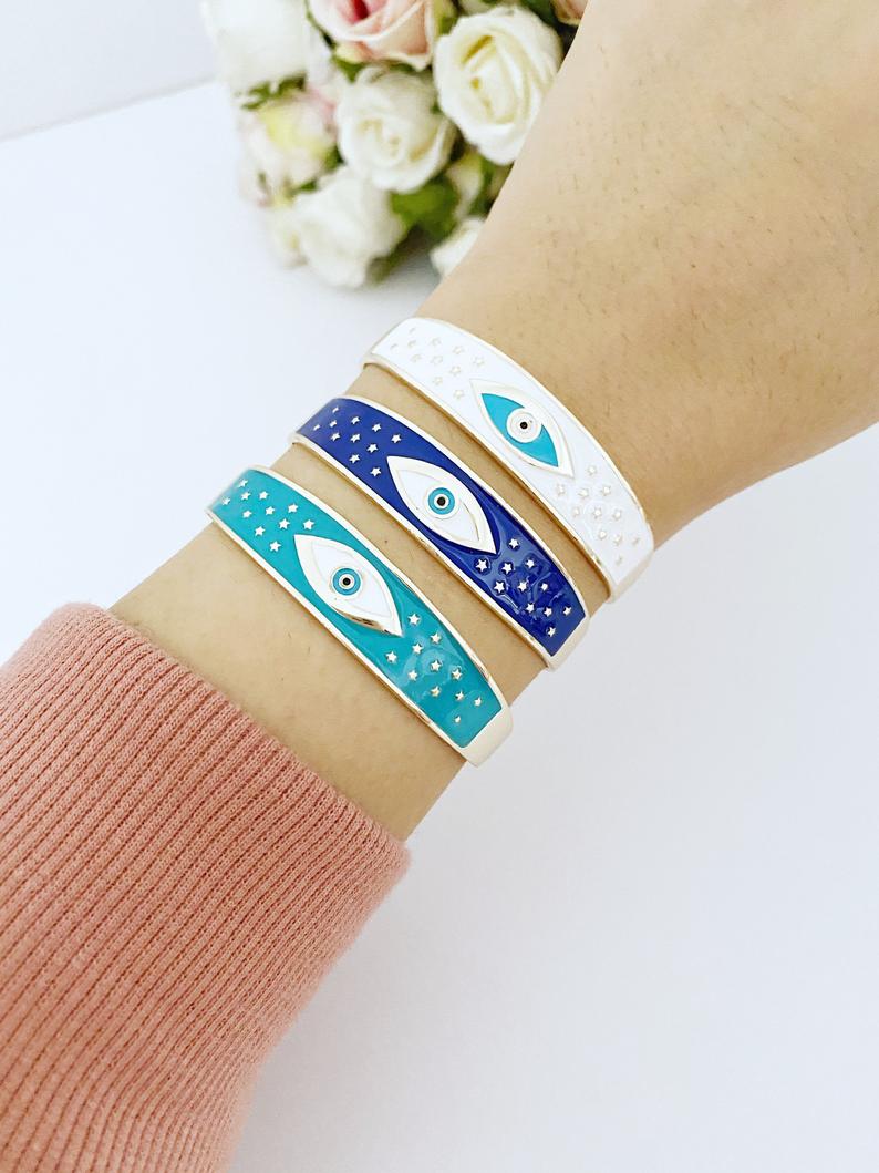 Adjustable Wide Cuff Bracelet featuring a movable Evil Eye charm in blue and gold, perfect for stacking.
