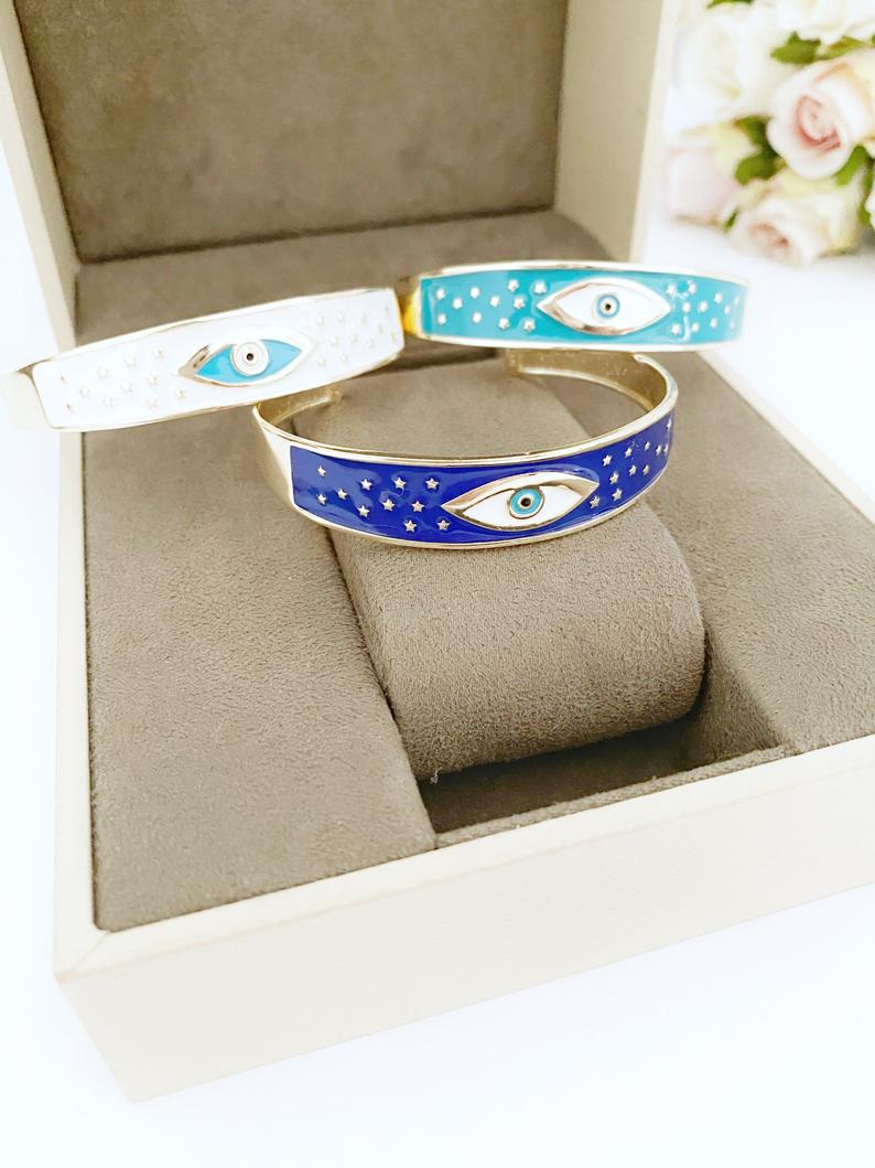 Adjustable Wide Cuff Bracelet featuring a movable Evil Eye charm in blue and gold, perfect for stacking.