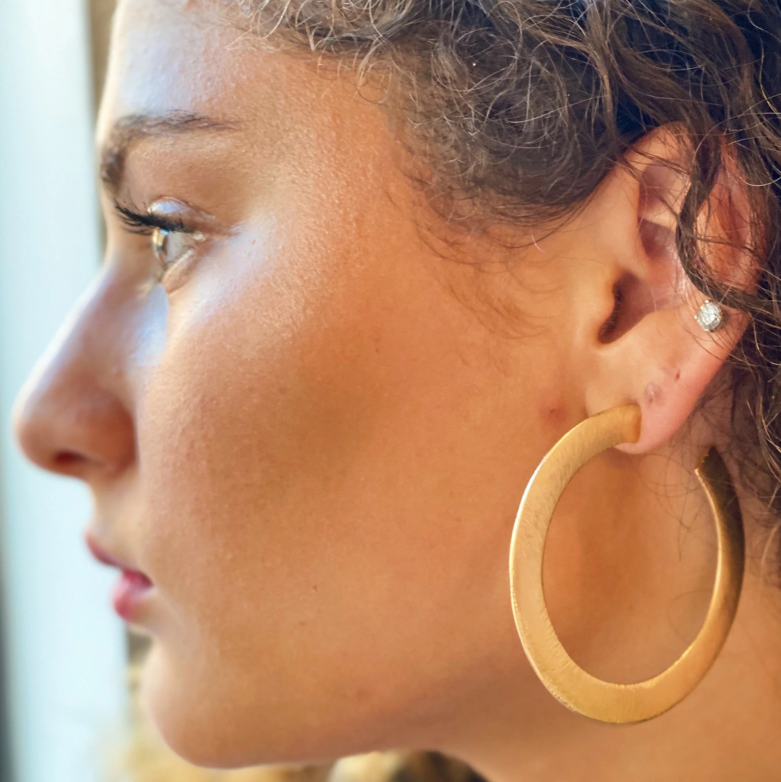 Alma Thick Flattened Metal Hoop Earrings in gold with a brushed texture, measuring 2.25 inches in diameter.