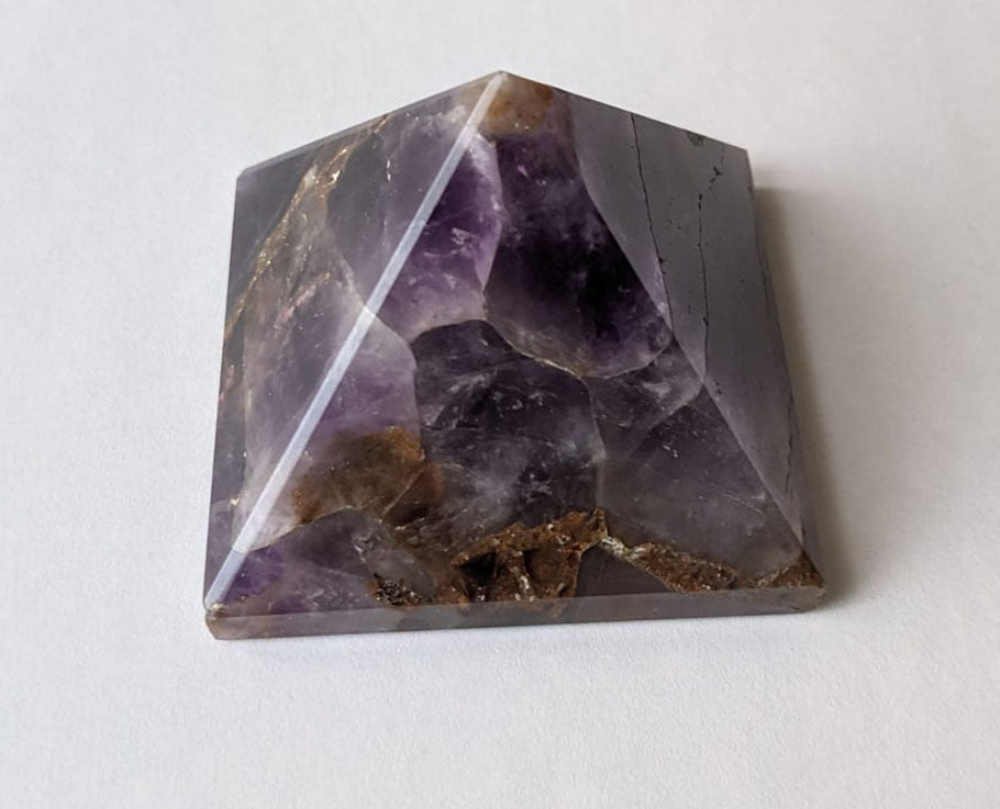 A hand-carved natural amethyst pyramid showcasing unique purple hues and textures, symbolizing healing and tranquility.