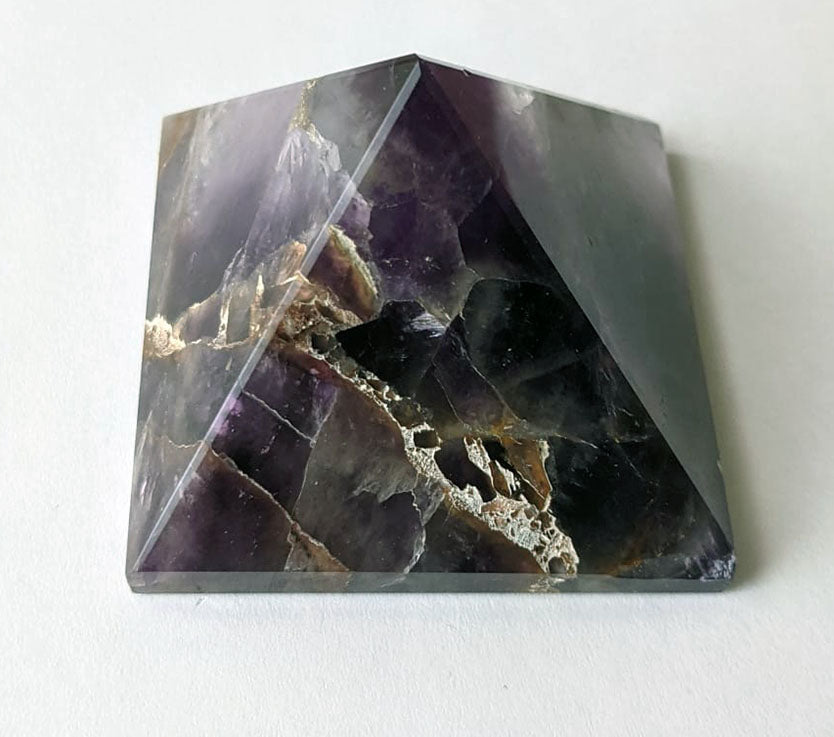 A hand-carved natural amethyst pyramid showcasing unique purple hues and textures, symbolizing healing and tranquility.