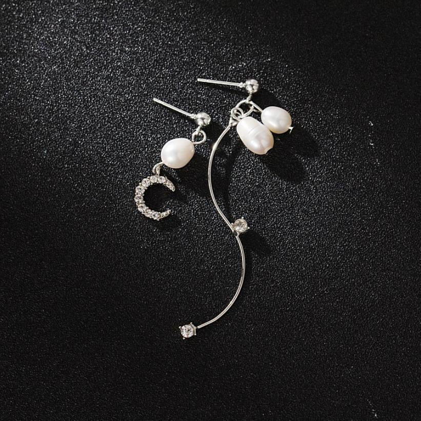 Asymmetric earrings featuring a moon design embellished with rhinestones and pearls, showcasing elegance and style.