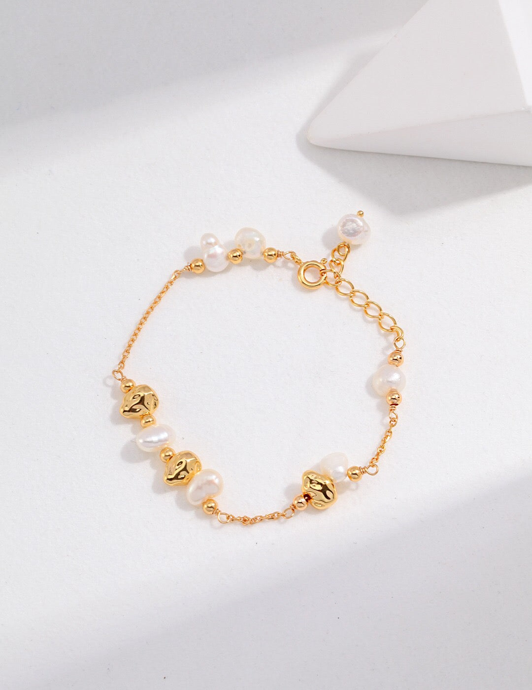 A handmade Baroque Pearl and Irregular Gold Ball Bracelet featuring natural pearls and gold vermeil, elegantly displayed on a soft surface.
