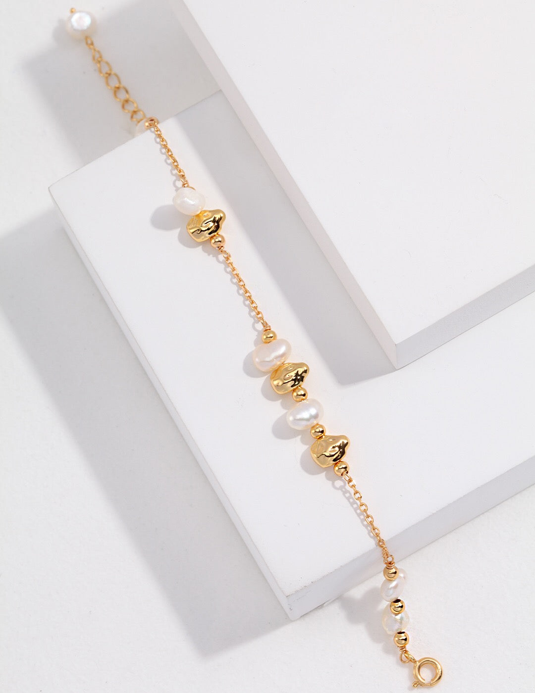 A handmade Baroque Pearl and Irregular Gold Ball Bracelet featuring natural pearls and gold vermeil, elegantly displayed on a soft surface.