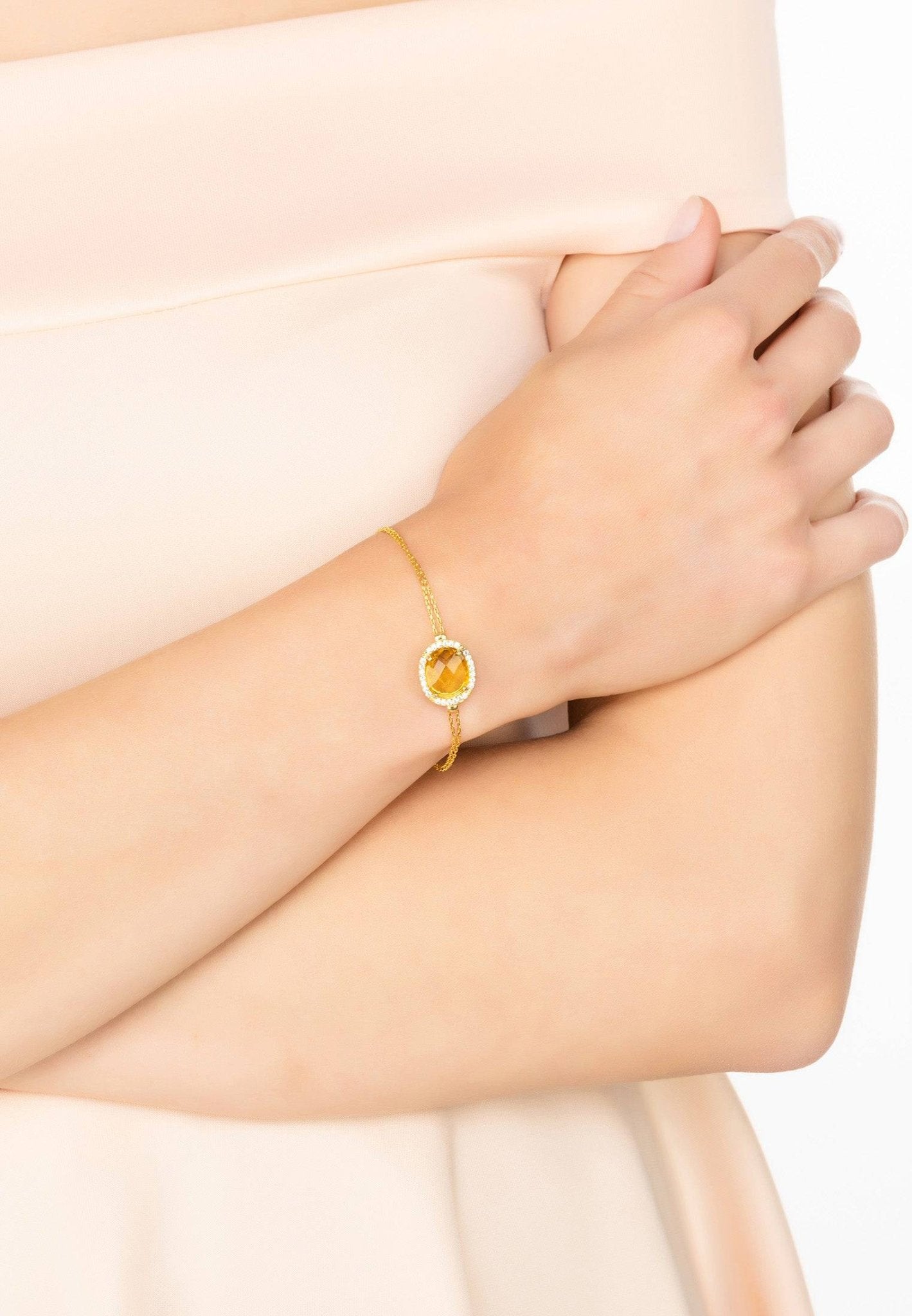 Beatrice Oval Gemstone Bracelet featuring a vibrant citrine surrounded by cubic zirconia on a gold plated double chain.