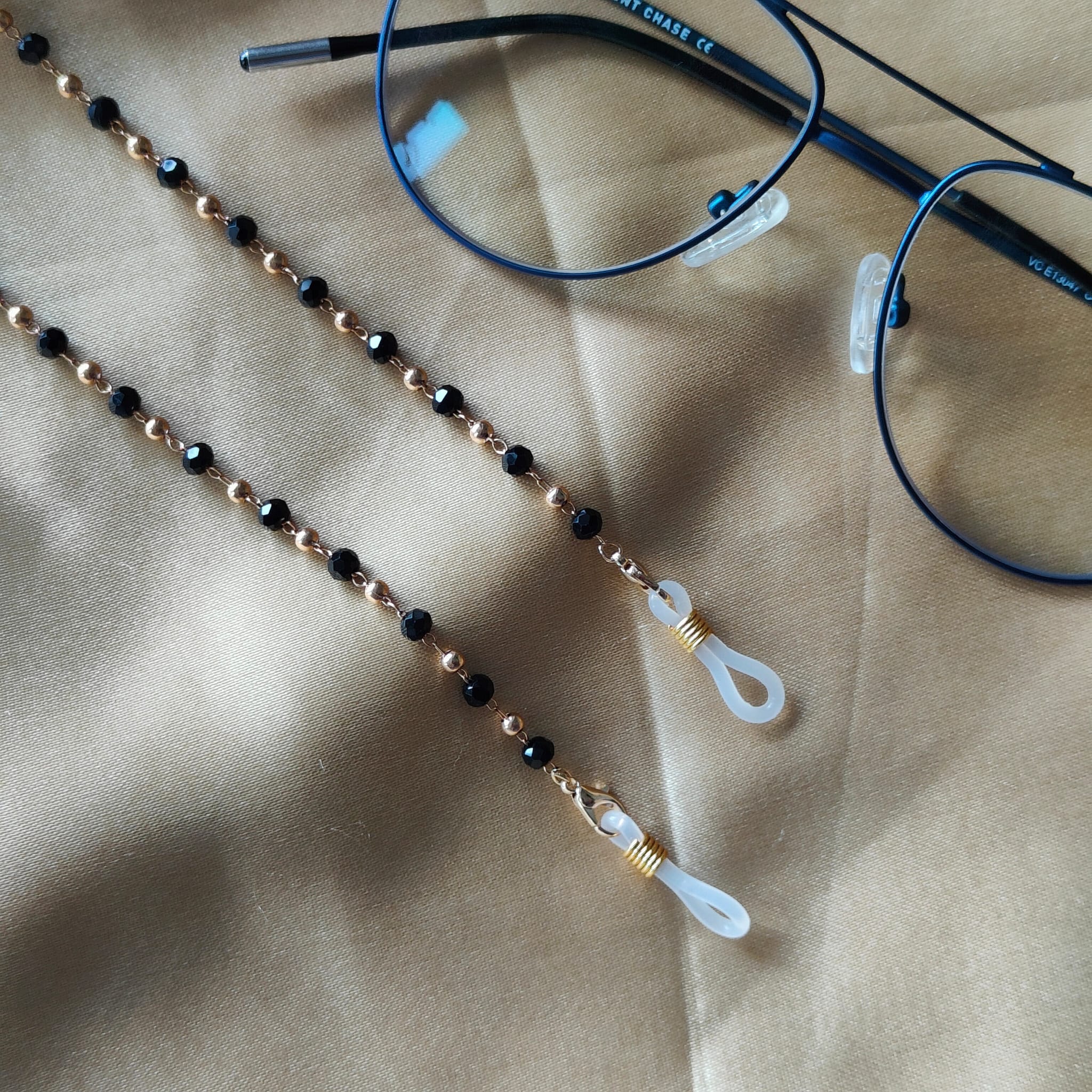 Black Beaded Sunglass Lanyard with Gold and Silver Plating, showcasing elegant design and versatility.