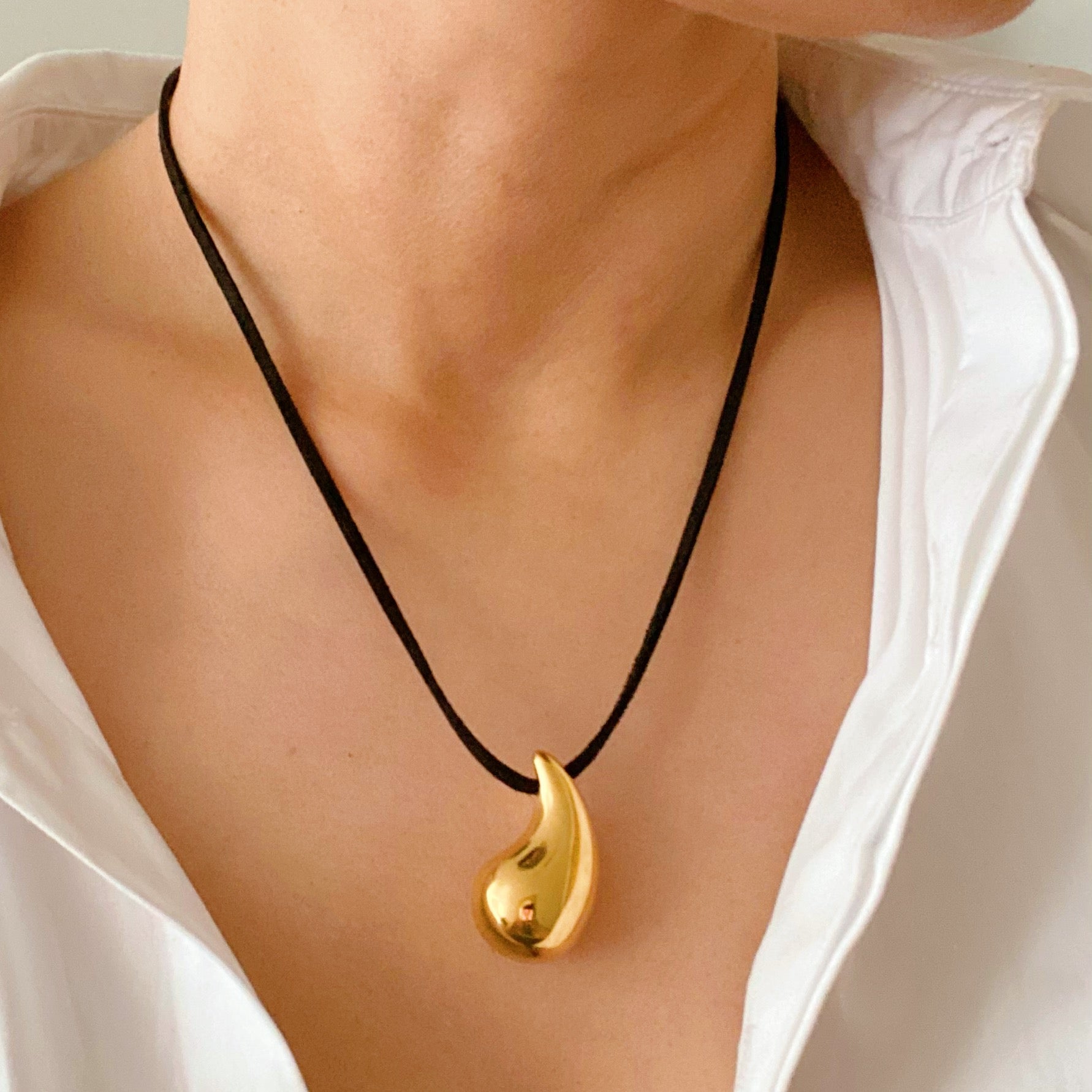 A stylish Black Leather Teardrop Necklace featuring a hollow teardrop pendant on a faux leather cord, elegantly displayed against a neutral background.