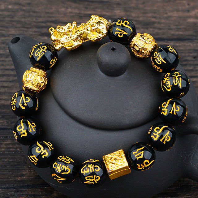 A stylish Black Obsidian Bracelet featuring natural obsidian stones with elegant gold writing accents, perfect for unisex wear.