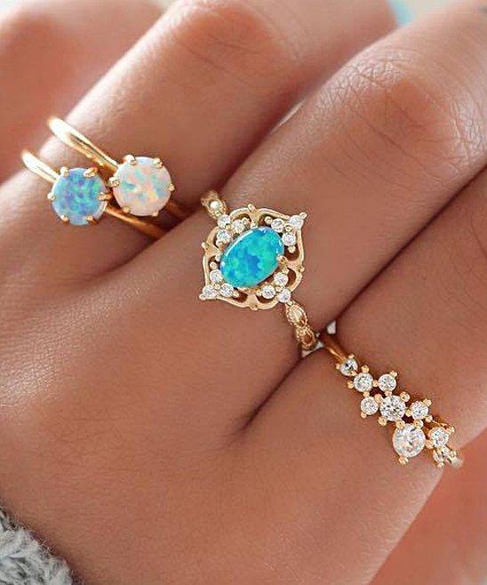 A set of four elegant blue and 18k gold-plated rings adorned with Austrian crystals, showcasing their intricate design and luxurious finish.