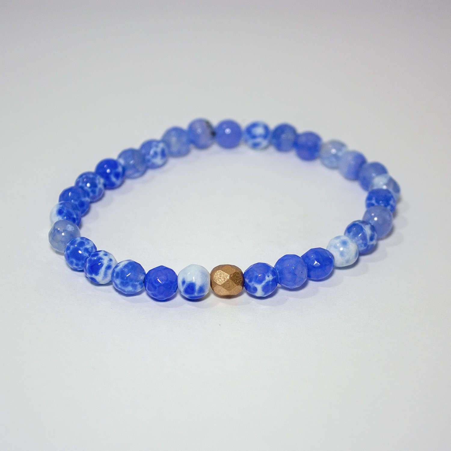 A vibrant blue crackled agate stretch bracelet with gold plated brass accents, showcasing its unique bead patterns.