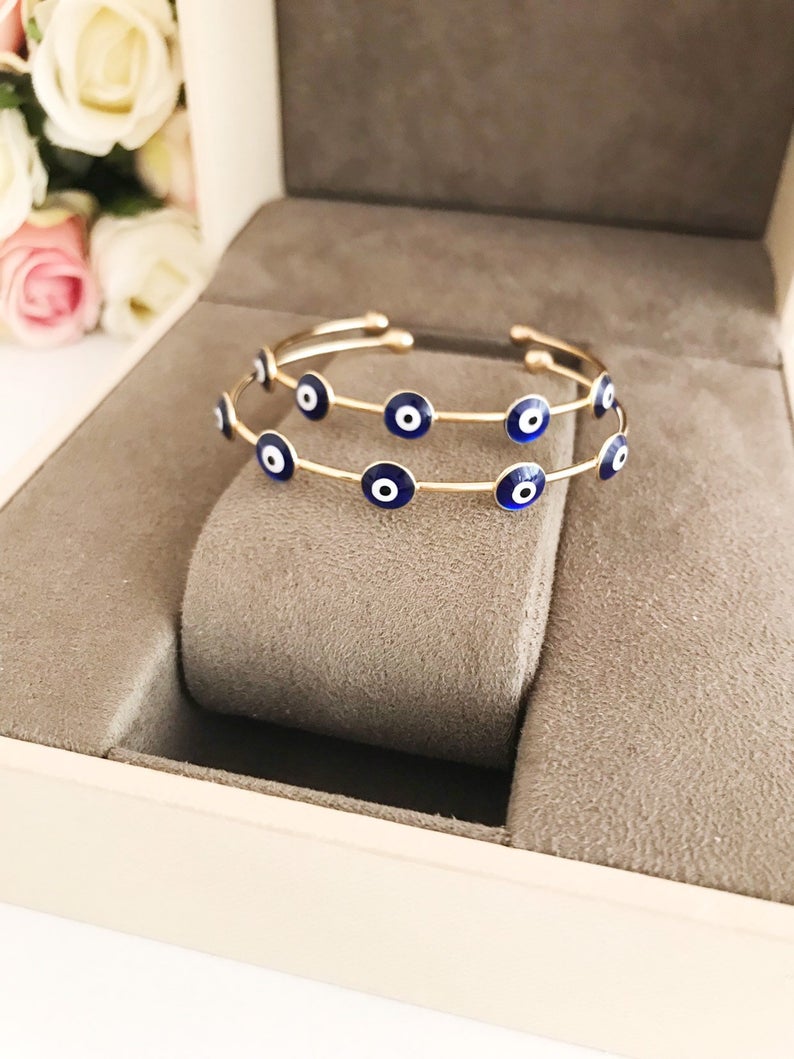 A beautiful Blue Evil Eye Bangle Bracelet featuring a movable oval charm and a round cuff design, crafted from durable stainless steel.
