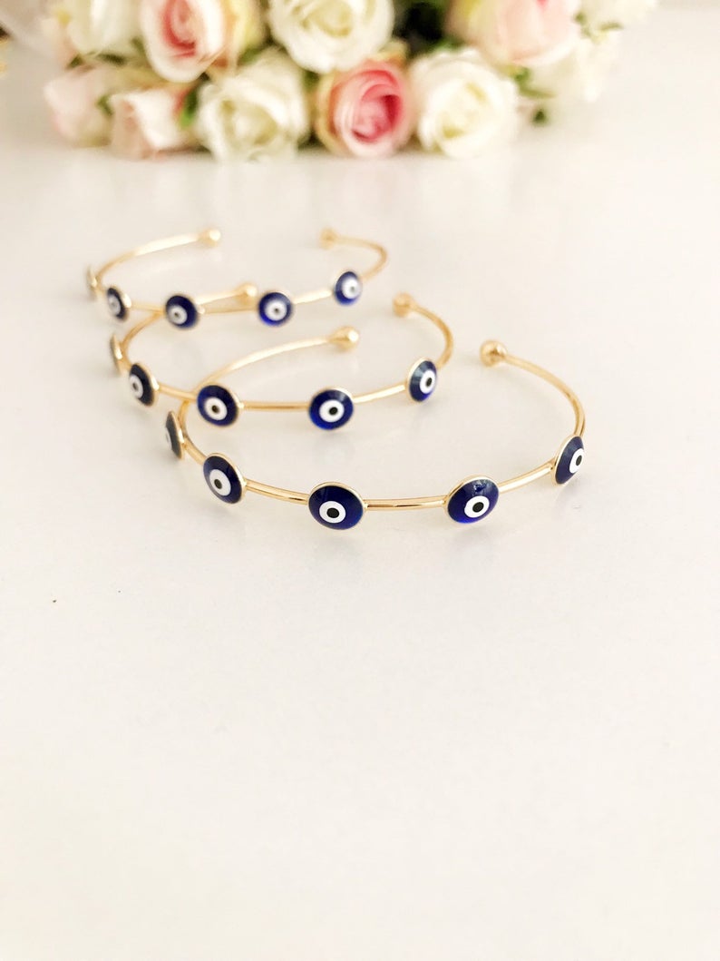 A beautiful Blue Evil Eye Bangle Bracelet featuring a movable oval charm and a round cuff design, crafted from durable stainless steel.