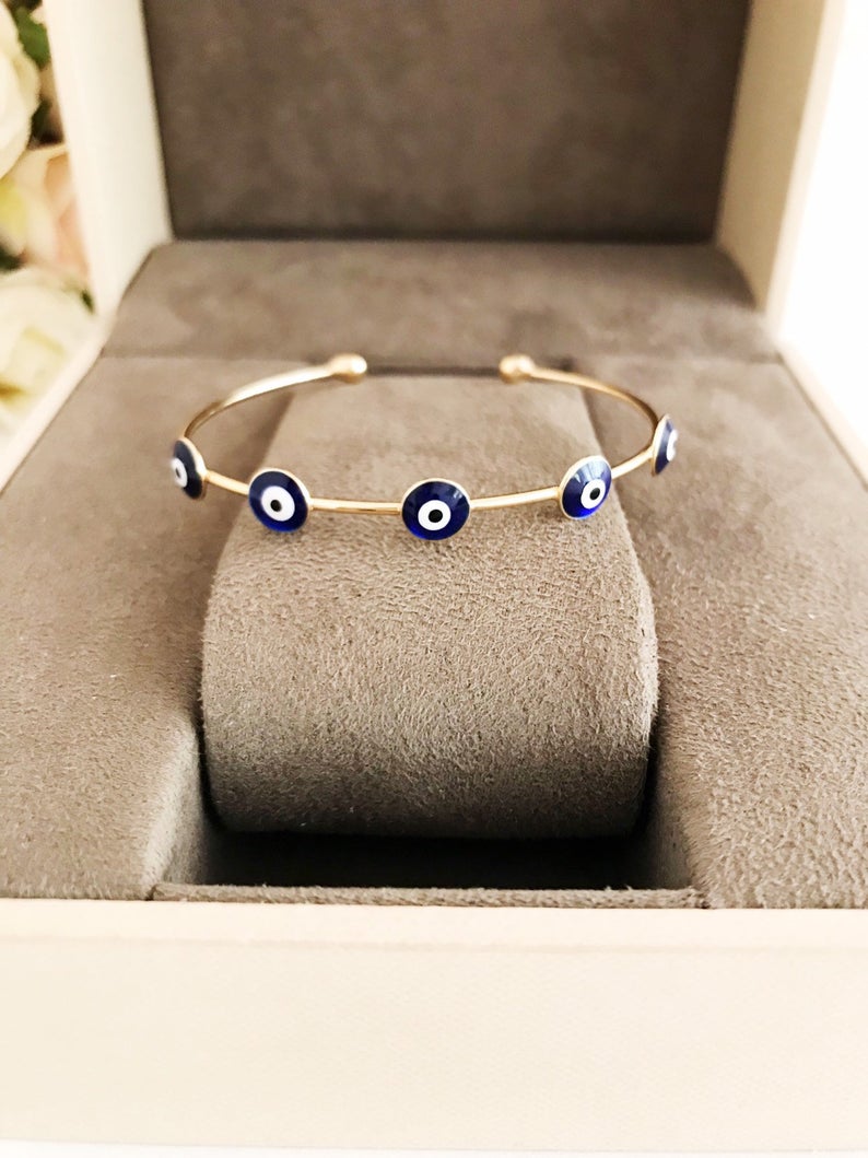 A beautiful Blue Evil Eye Bangle Bracelet featuring a movable oval charm and a round cuff design, crafted from durable stainless steel.