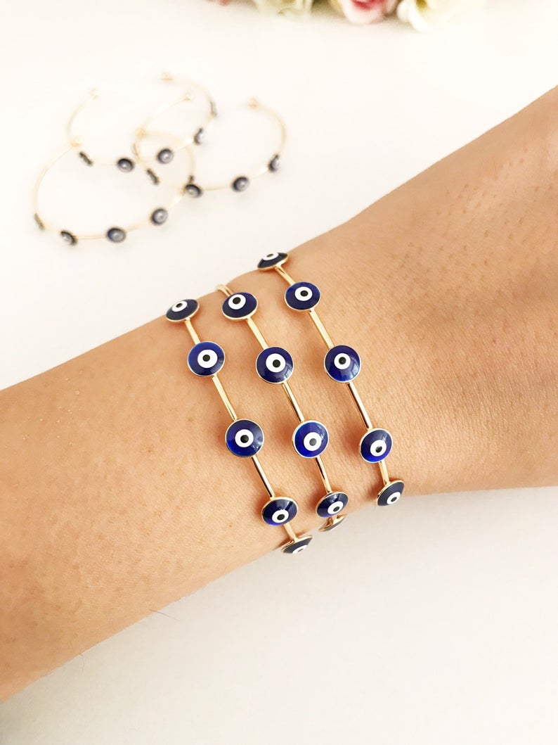 A beautiful Blue Evil Eye Bangle Bracelet featuring a movable oval charm and a round cuff design, crafted from durable stainless steel.