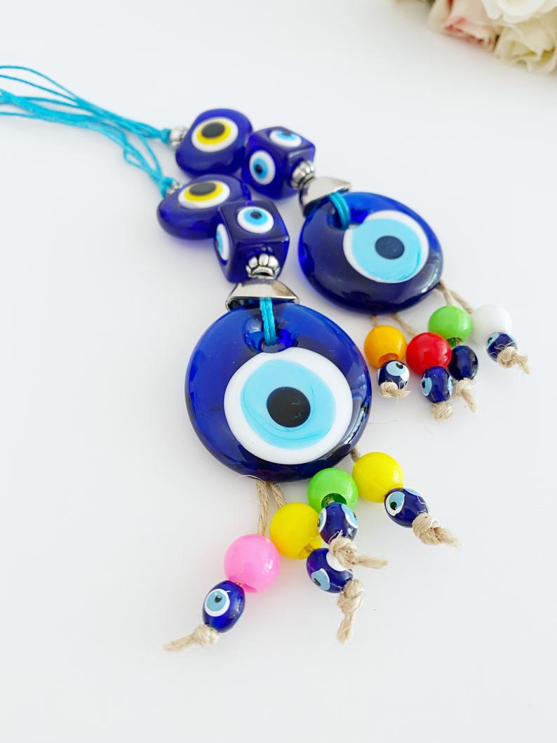 A beautiful Blue Evil Eye Bead car accessory, featuring a glass bead with a traditional Nazar design, hanging elegantly from a string.