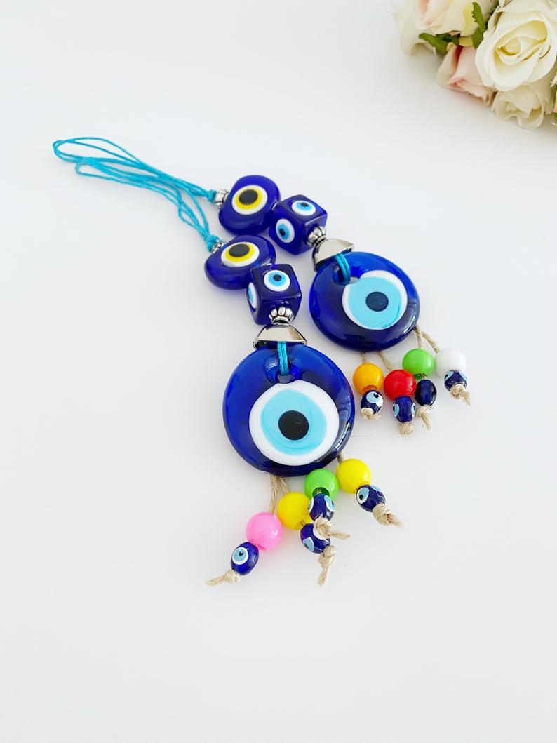 A beautiful Blue Evil Eye Bead car accessory, featuring a glass bead with a traditional Nazar design, hanging elegantly from a string.