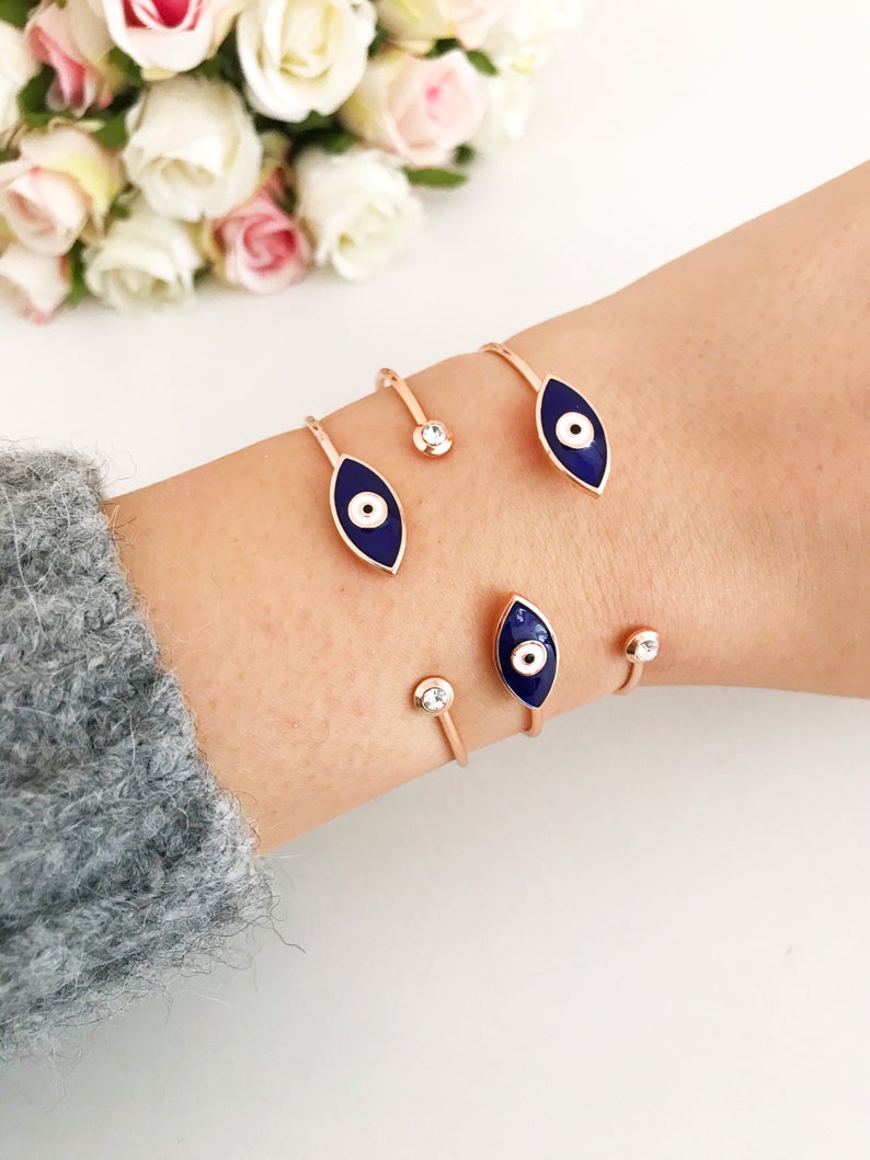 A stylish blue evil eye bracelet featuring a movable charm and rose gold cuff design, made from durable stainless steel.