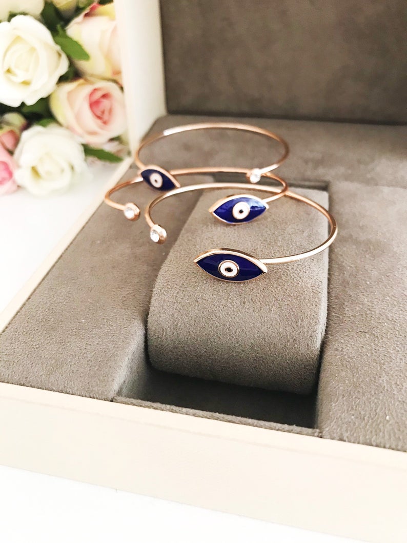 A stylish blue evil eye bracelet featuring a movable charm and rose gold cuff design, made from durable stainless steel.