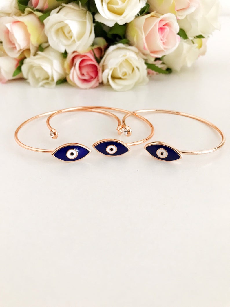 A stylish blue evil eye bracelet featuring a movable charm and rose gold cuff design, made from durable stainless steel.