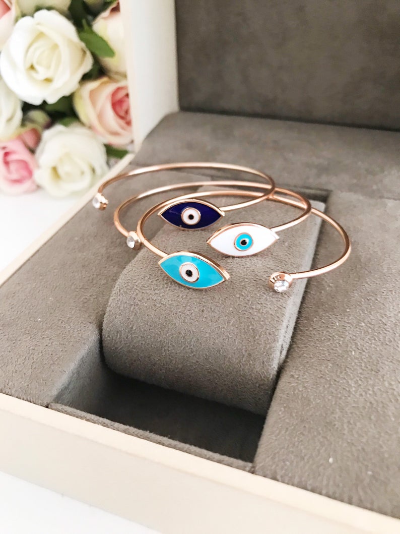 A stylish blue evil eye bracelet featuring a movable charm and rose gold cuff design, made from durable stainless steel.