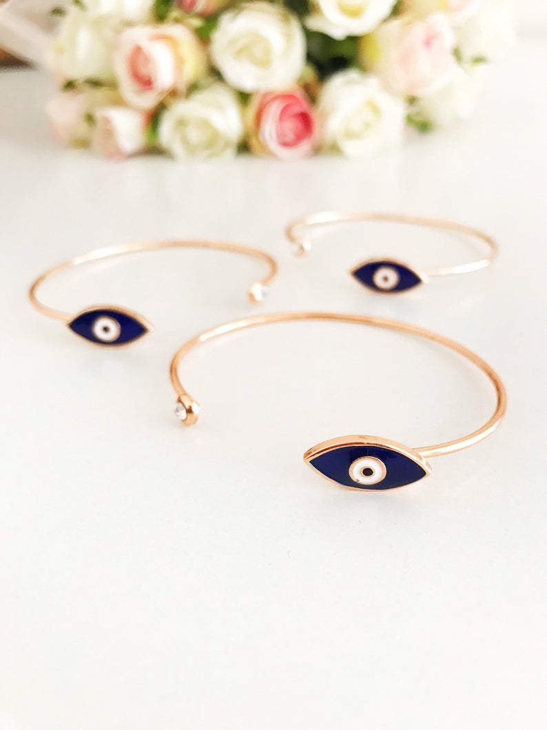 A stylish blue evil eye bracelet featuring a movable charm and rose gold cuff design, made from durable stainless steel.