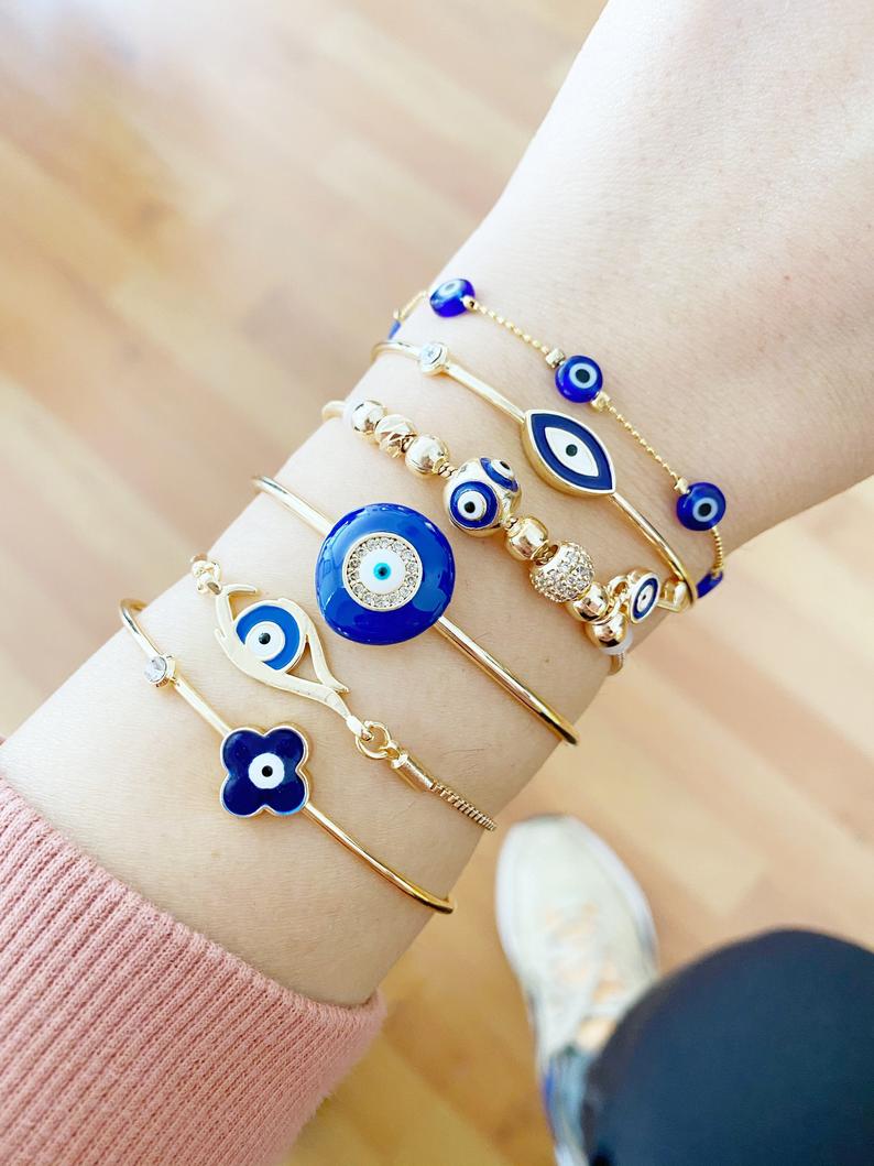 A beautiful Blue Evil Eye Bracelet featuring a gold cuff design, handmade from tarnish-resistant stainless steel.