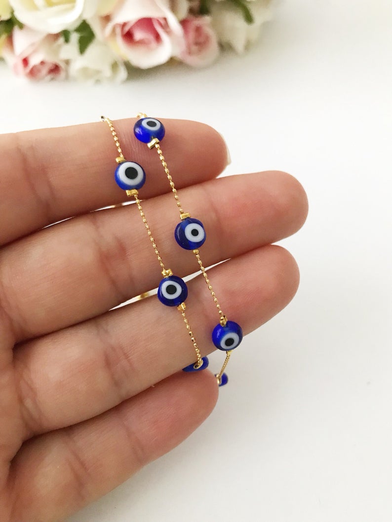 A dainty blue evil eye bracelet featuring a gold chain and five tiny blue glass beads, elegantly designed for everyday wear.