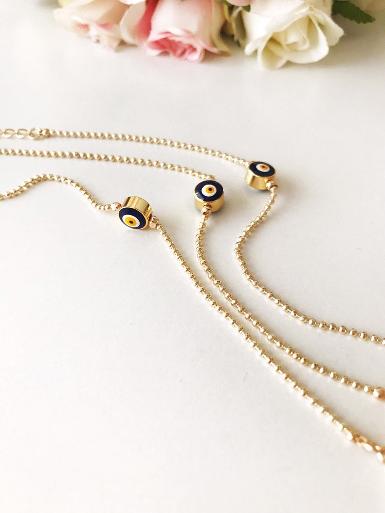 A stylish blue evil eye bracelet featuring a gold chain and blue beads, symbolizing protection and elegance.