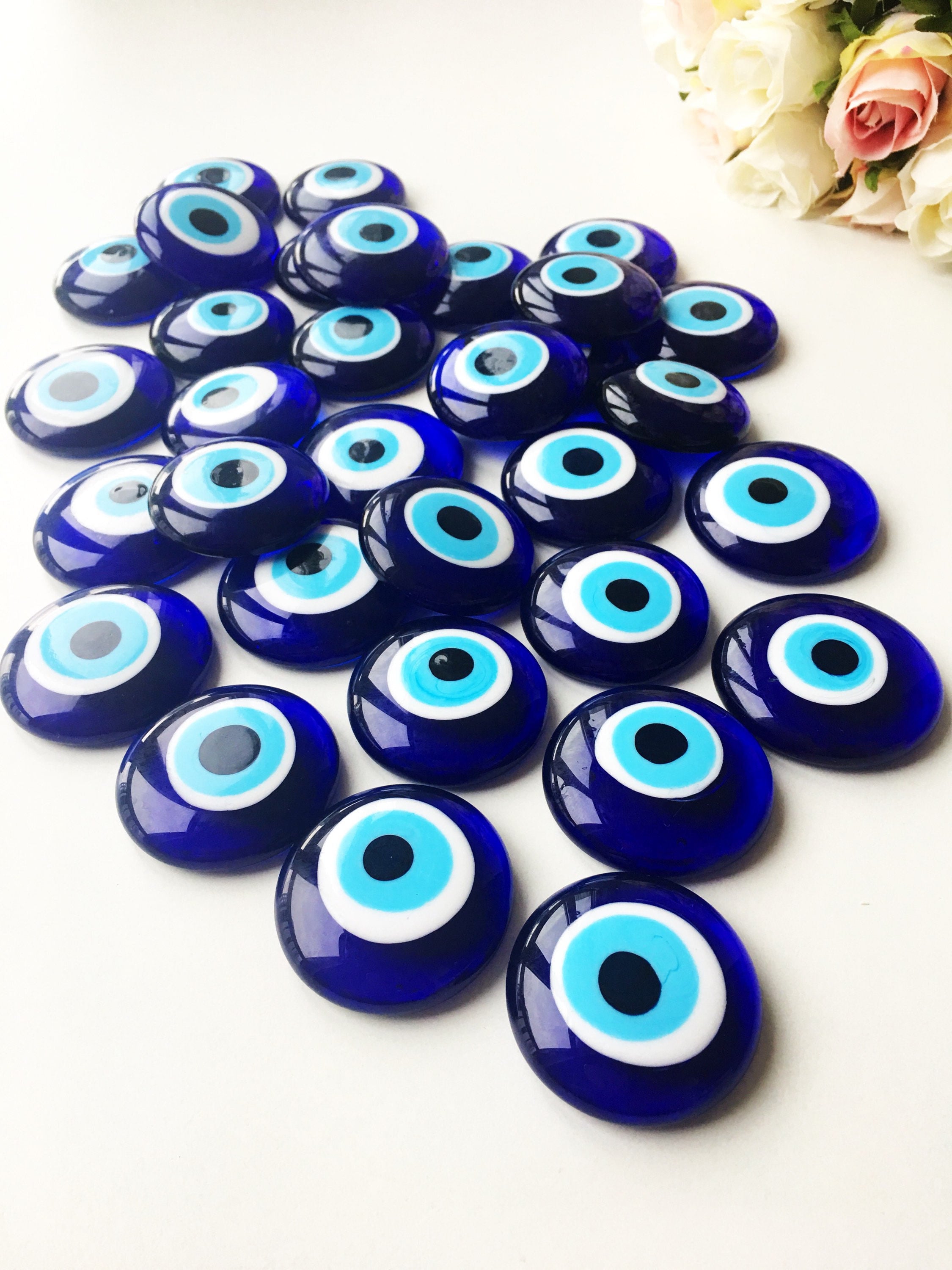 A collection of blue evil eye charm beads made of glass, showcasing their vibrant color and round shape, ideal for crafts and protection.
