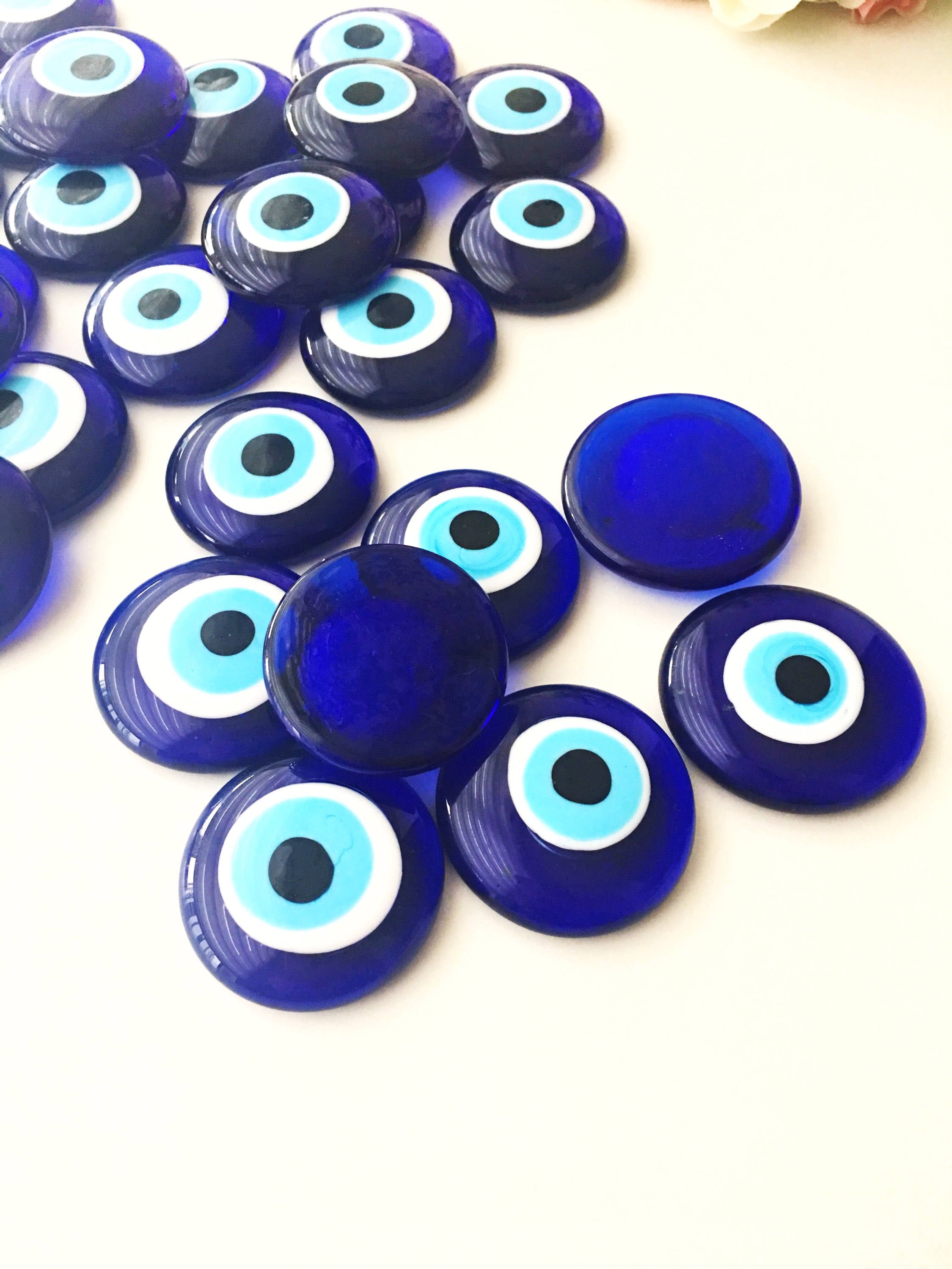 A collection of blue evil eye charm beads made of glass, showcasing their vibrant color and round shape, ideal for crafts and protection.