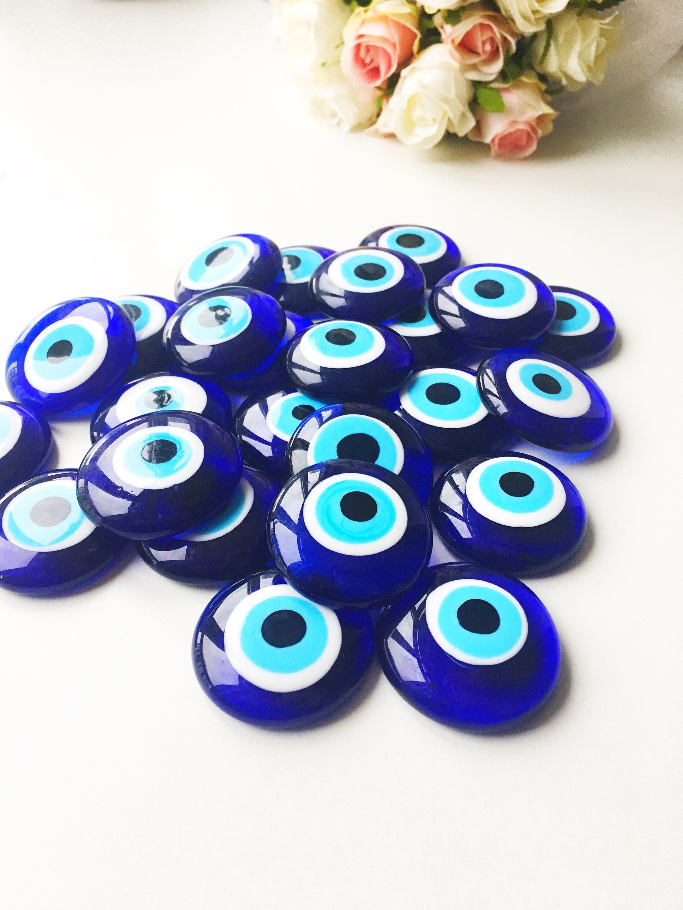 A collection of blue evil eye charm beads made of glass, showcasing their vibrant color and round shape, ideal for crafts and protection.