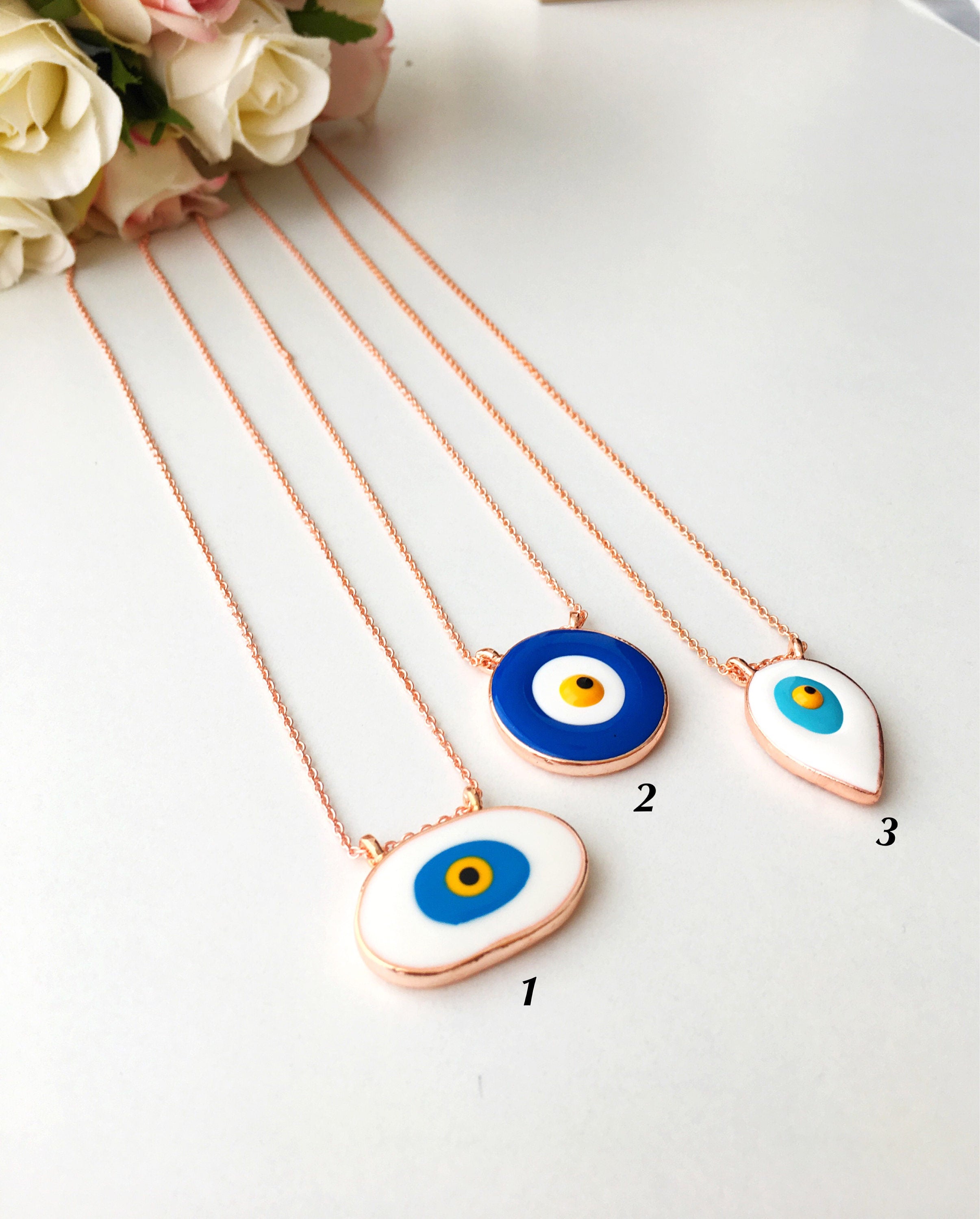 A beautiful Blue Evil Eye Necklace featuring white and blue enamel charms on a rose gold stainless steel chain, symbolizing protection and good luck.