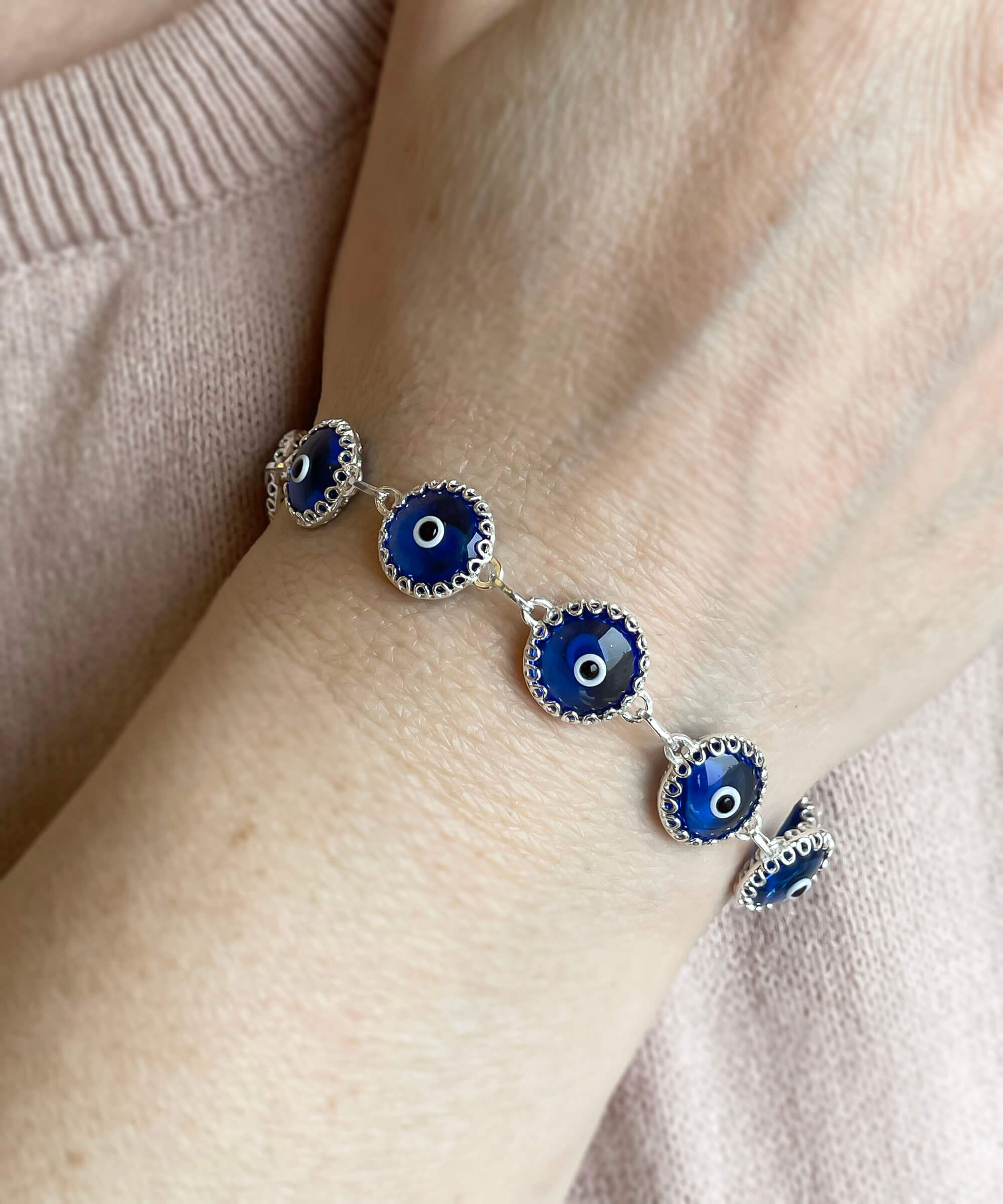 Blue Evil Eye Sterling Silver Adjustable Link Bracelet featuring a strong rolo chain and ten blue evil eye beads wrapped in silver prongs.