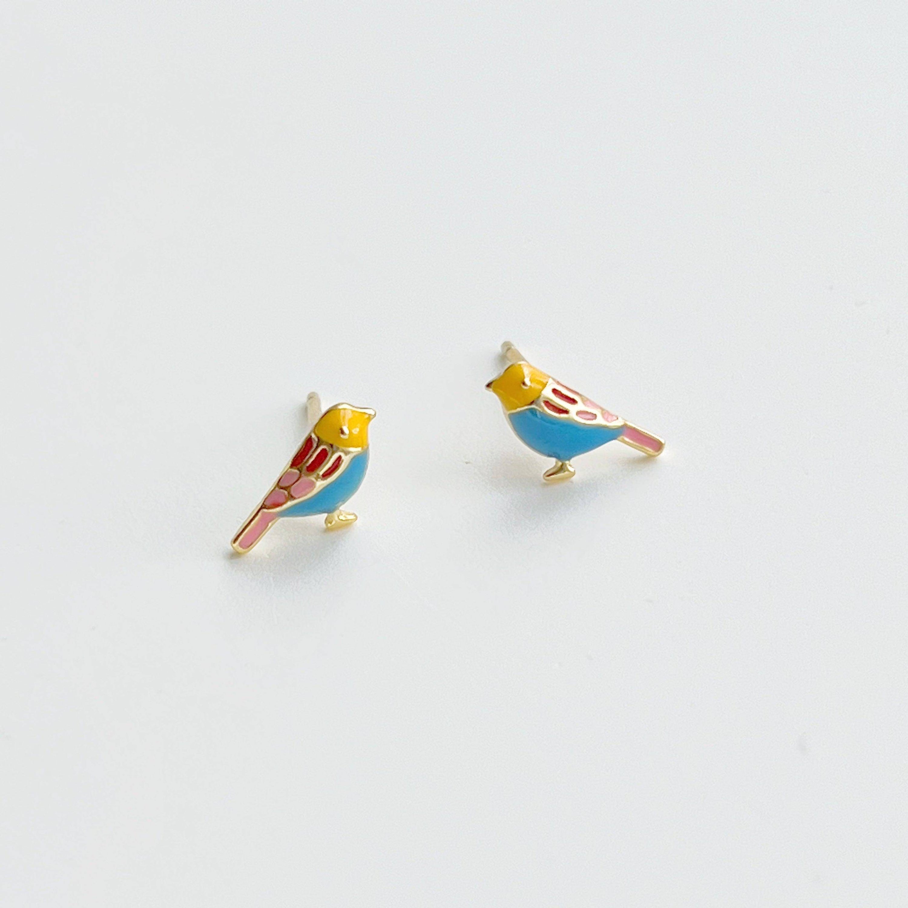 A pair of tiny blue robin earrings in sterling silver, shaped like lucky birds, displayed elegantly in a gift box.