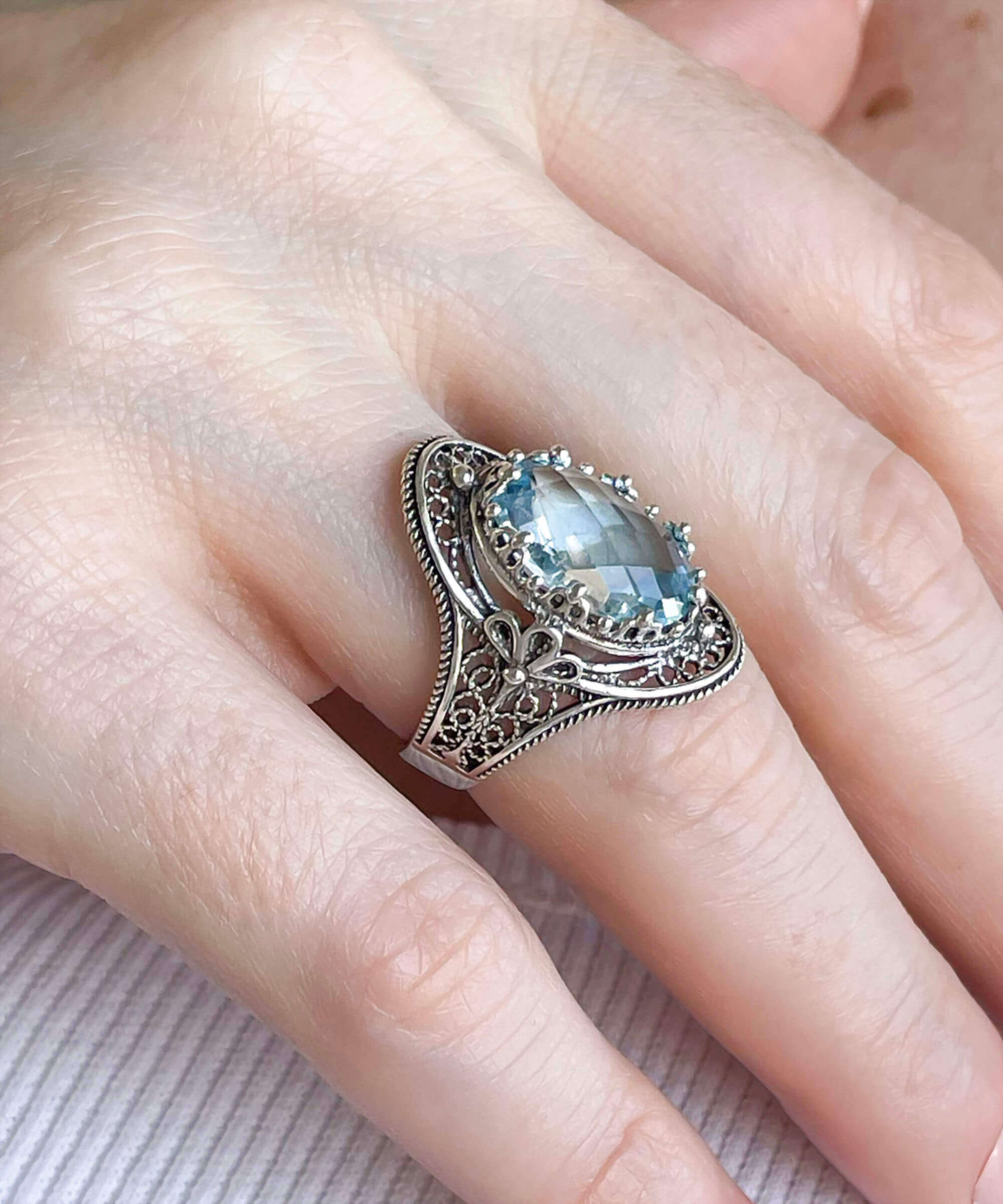 A stunning handmade silver statement ring featuring a blue topaz gemstone with intricate filigree art design.