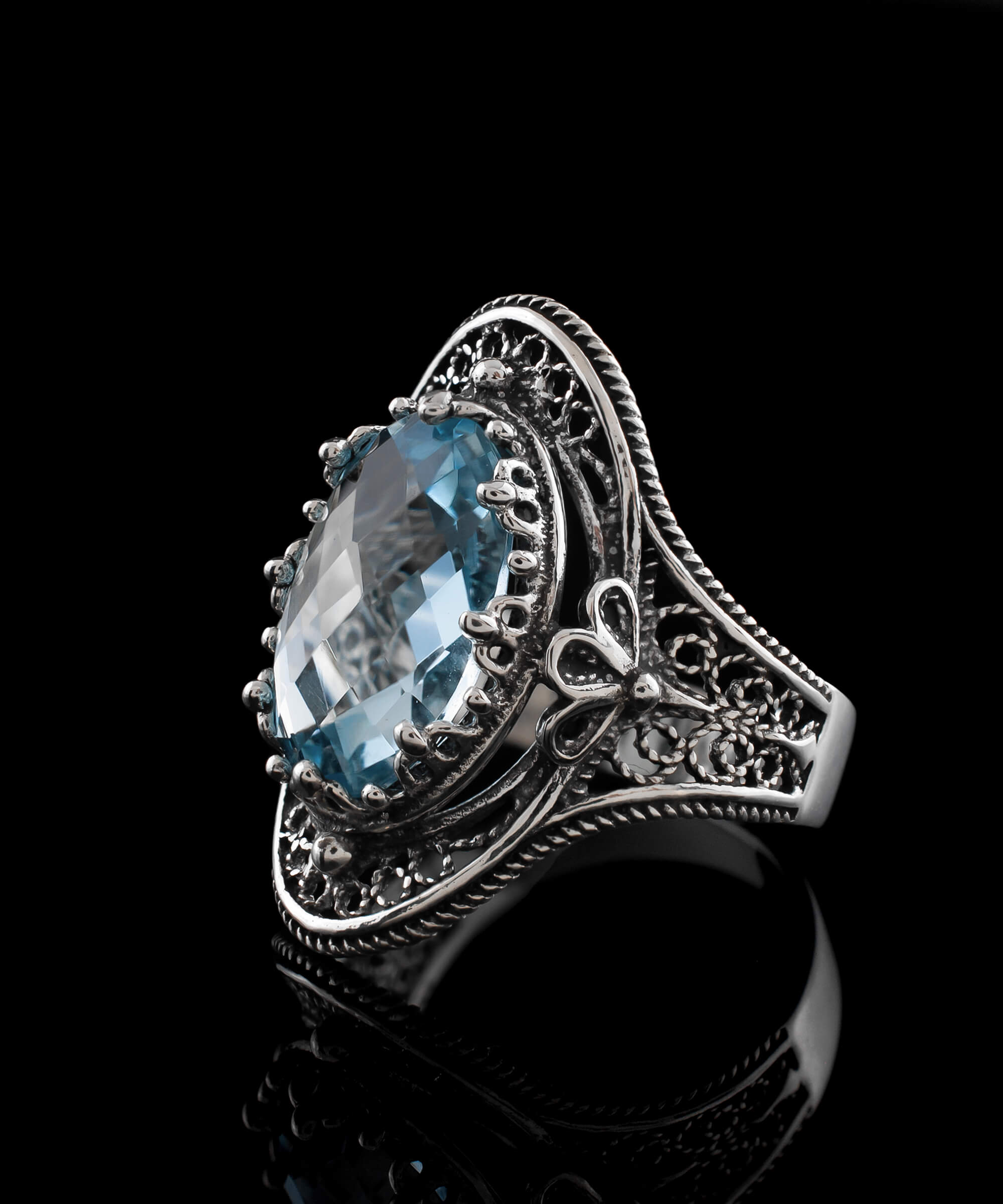 A stunning handmade silver statement ring featuring a blue topaz gemstone with intricate filigree art design.