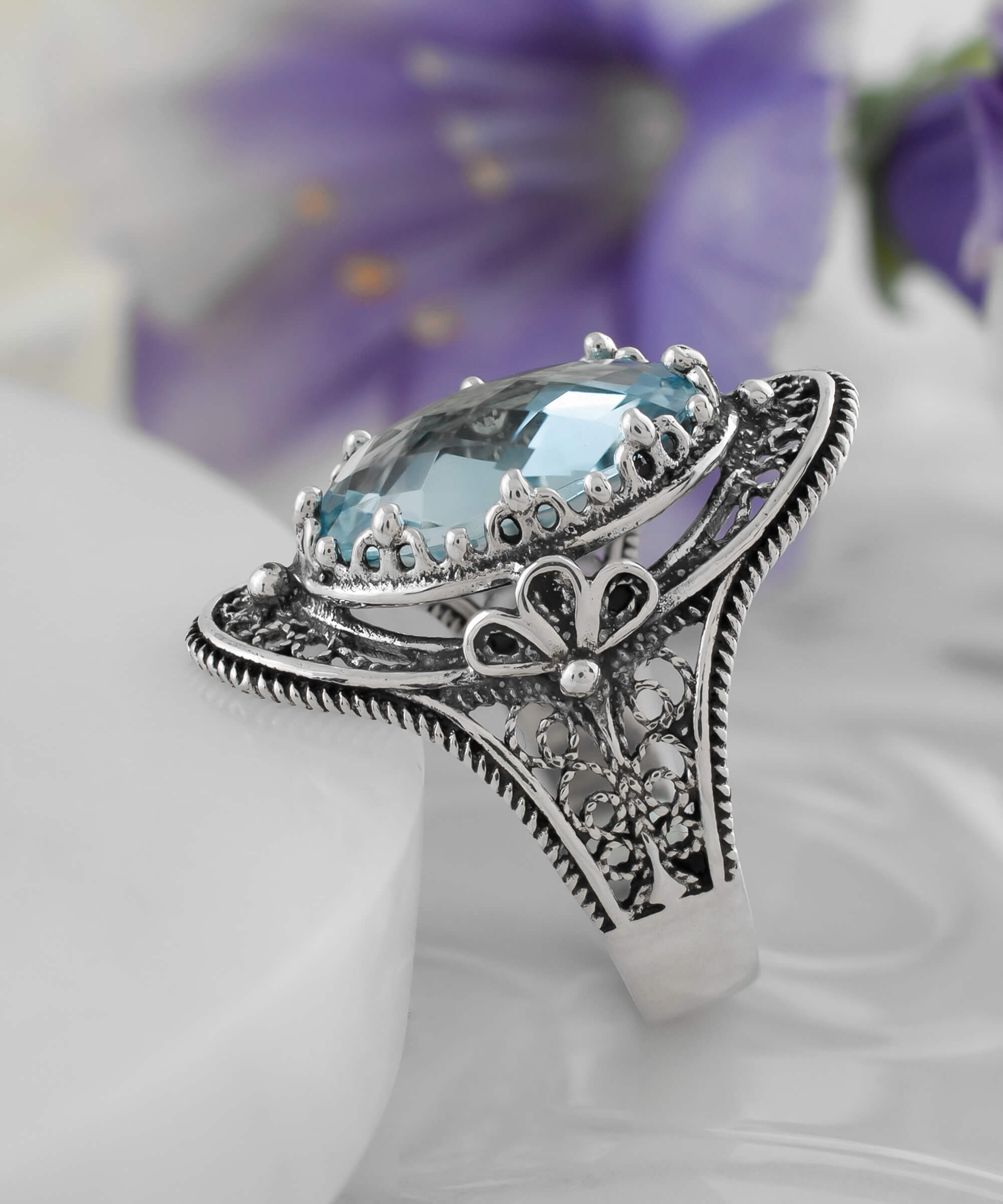 A stunning handmade silver statement ring featuring a blue topaz gemstone with intricate filigree art design.