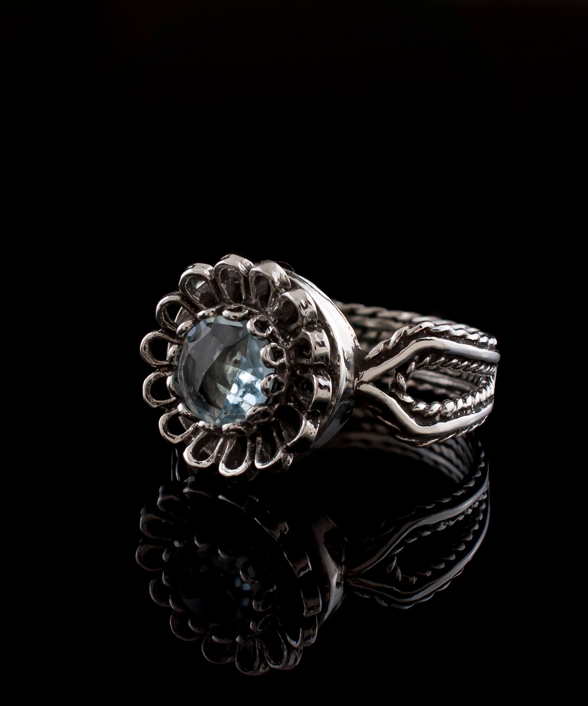 A beautiful Blue Topaz Gemstone Sterling Silver Cocktail Ring featuring a delicate lace flower design and a sparkling sky blue topaz.