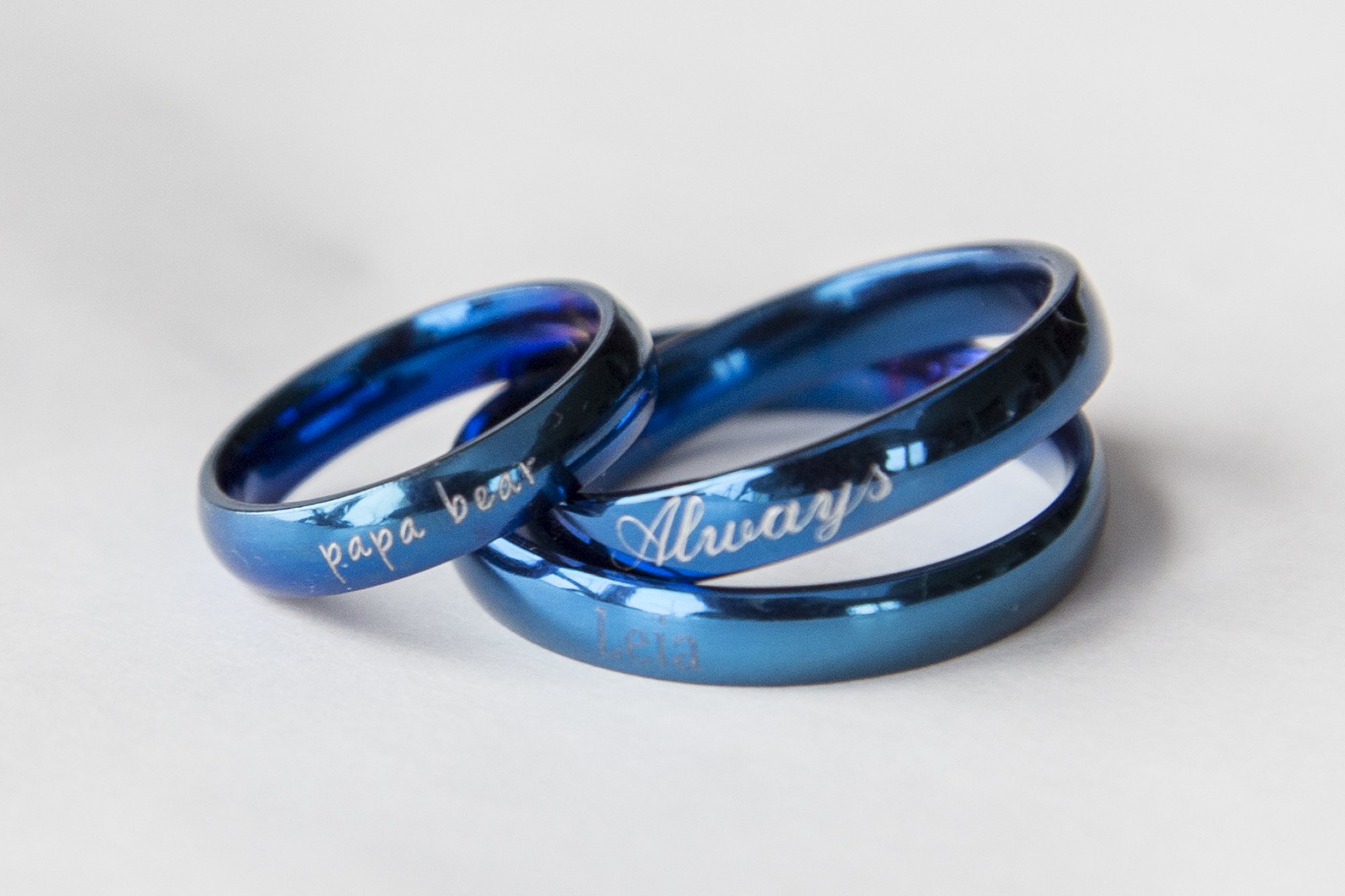 A blue stainless steel ring with a shiny finish, featuring an engraving option for personalization, ideal for gifting.