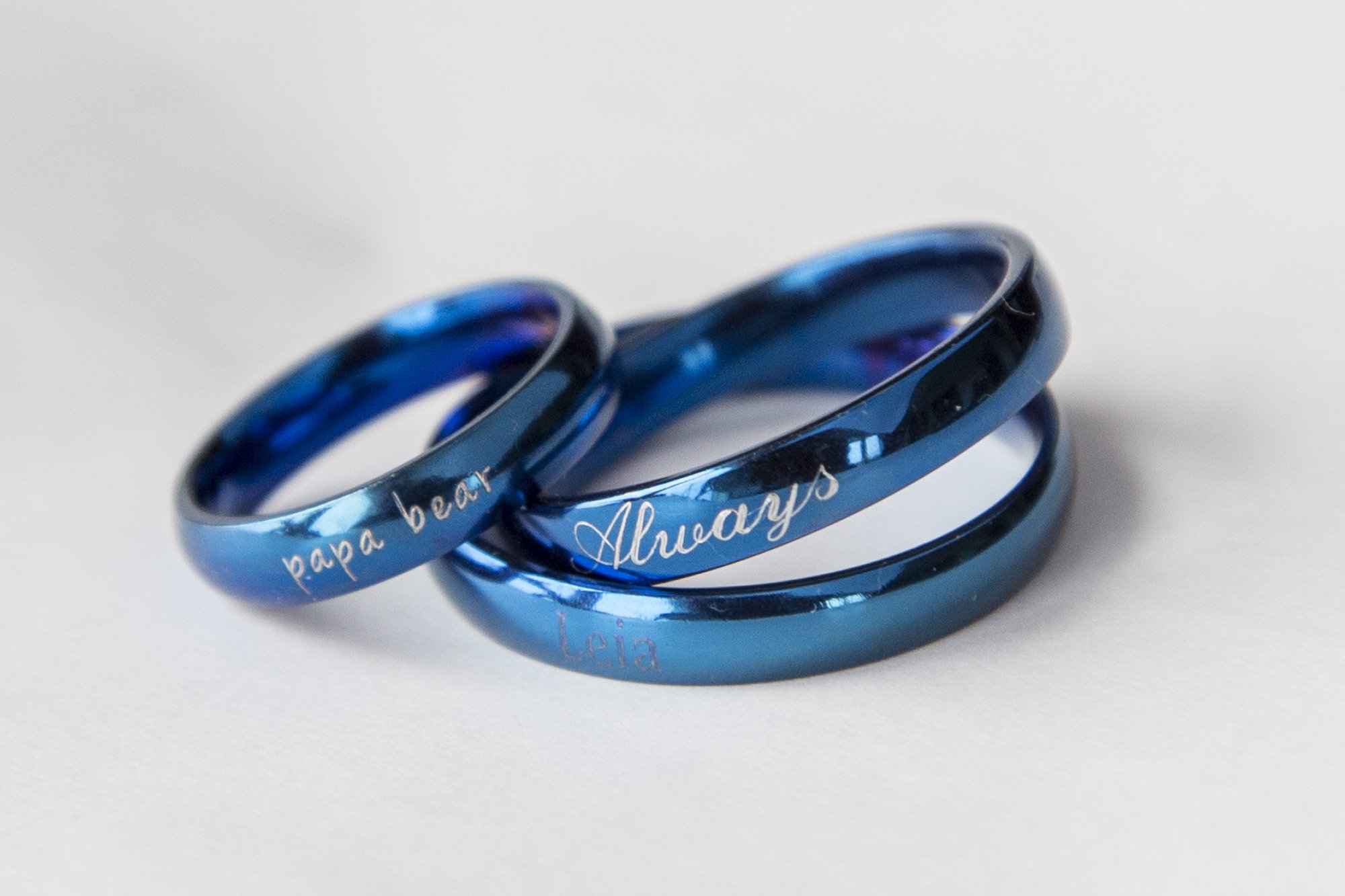 A blue stainless steel ring with a shiny finish, featuring an engraving option for personalization, ideal for gifting.