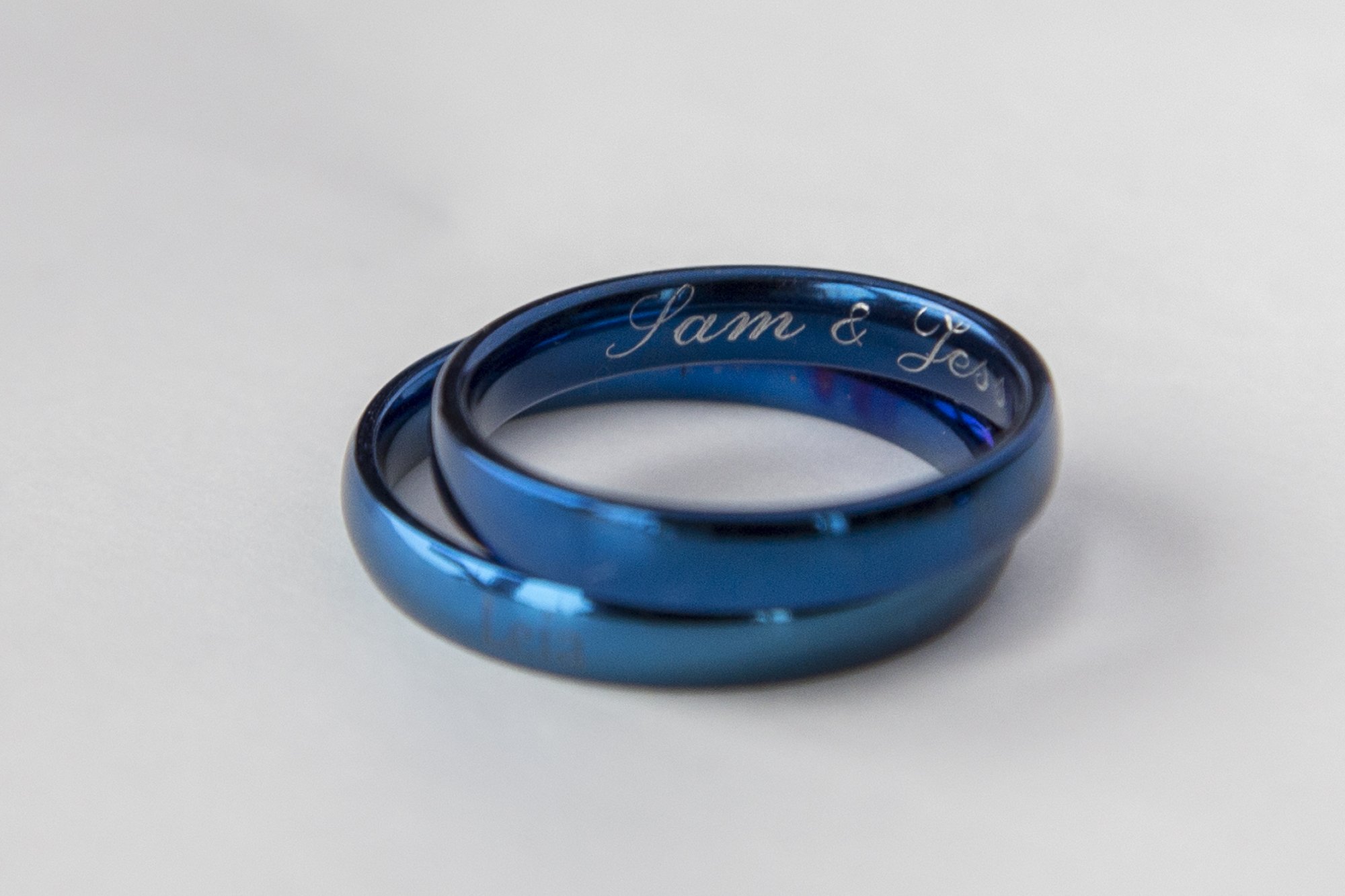 A blue stainless steel ring with a shiny finish, featuring an engraving option for personalization, ideal for gifting.