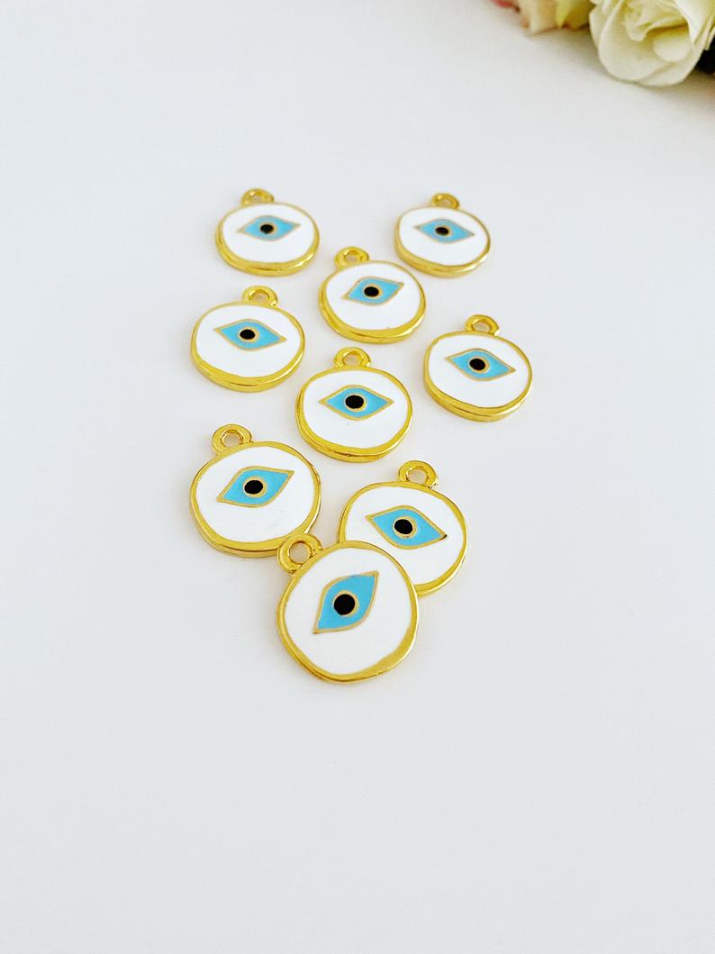 A detailed view of a brass evil eye bead featuring a white design, perfect for jewelry making and protection charms.