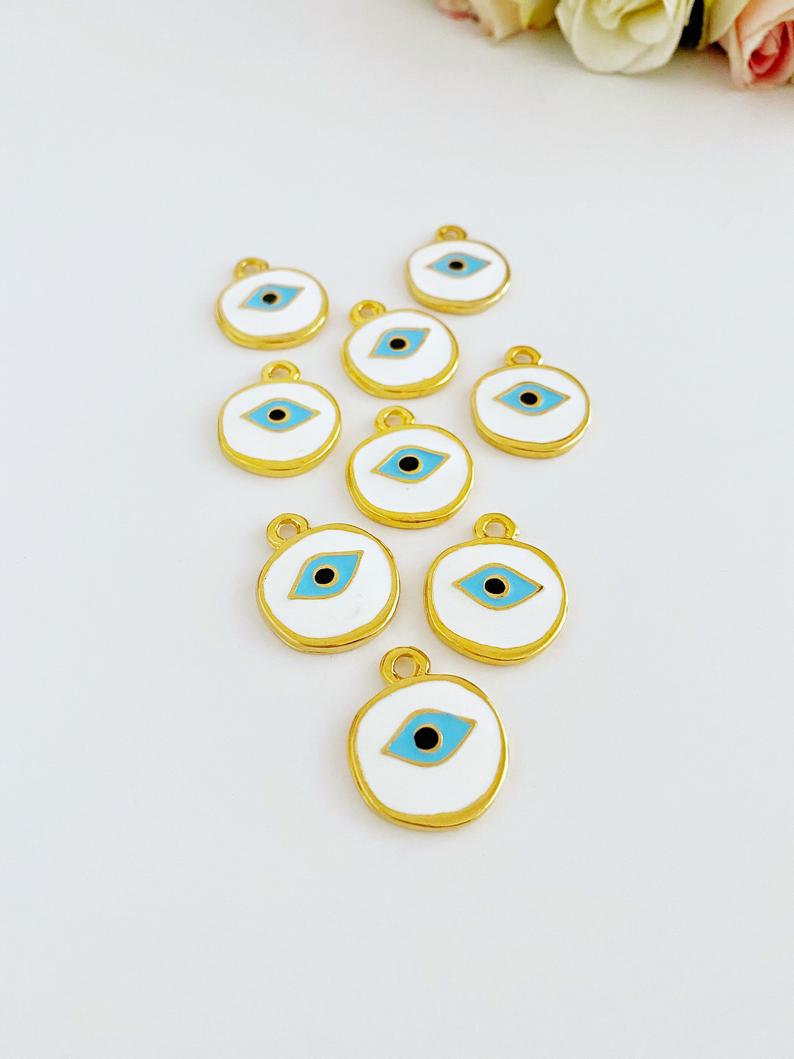 A detailed view of a brass evil eye bead featuring a white design, perfect for jewelry making and protection charms.