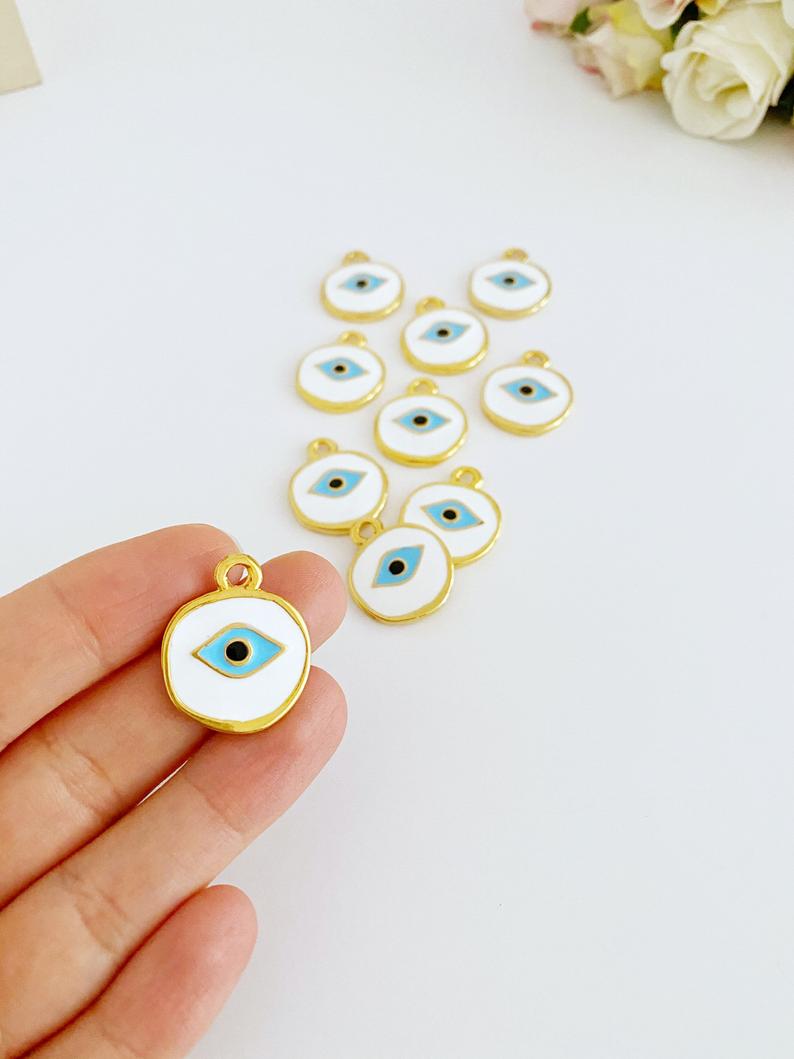 A detailed view of a brass evil eye bead featuring a white design, perfect for jewelry making and protection charms.