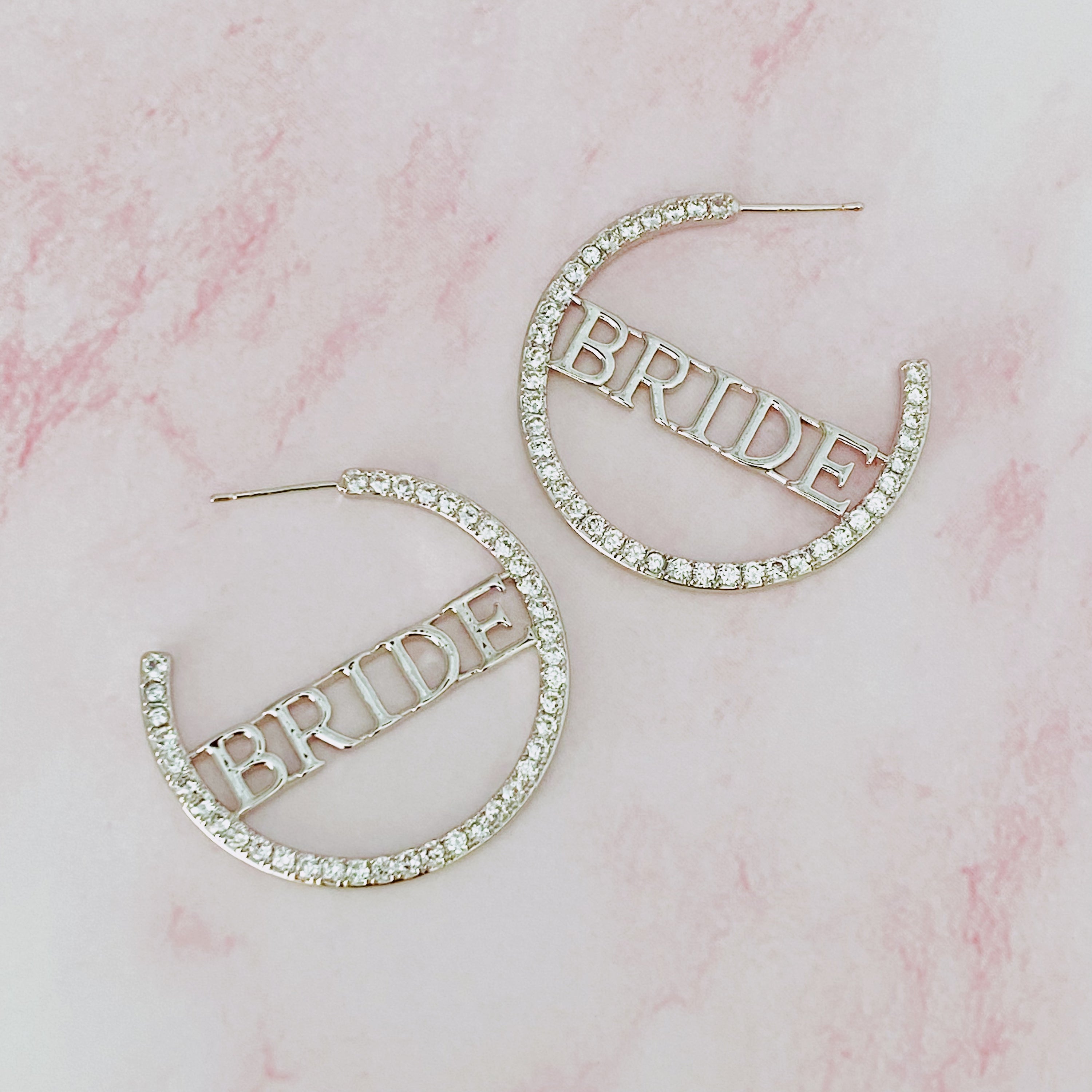 Elegant silver hoop earrings with 'BRIDE' engraving and sparkling accents, perfect for brides.