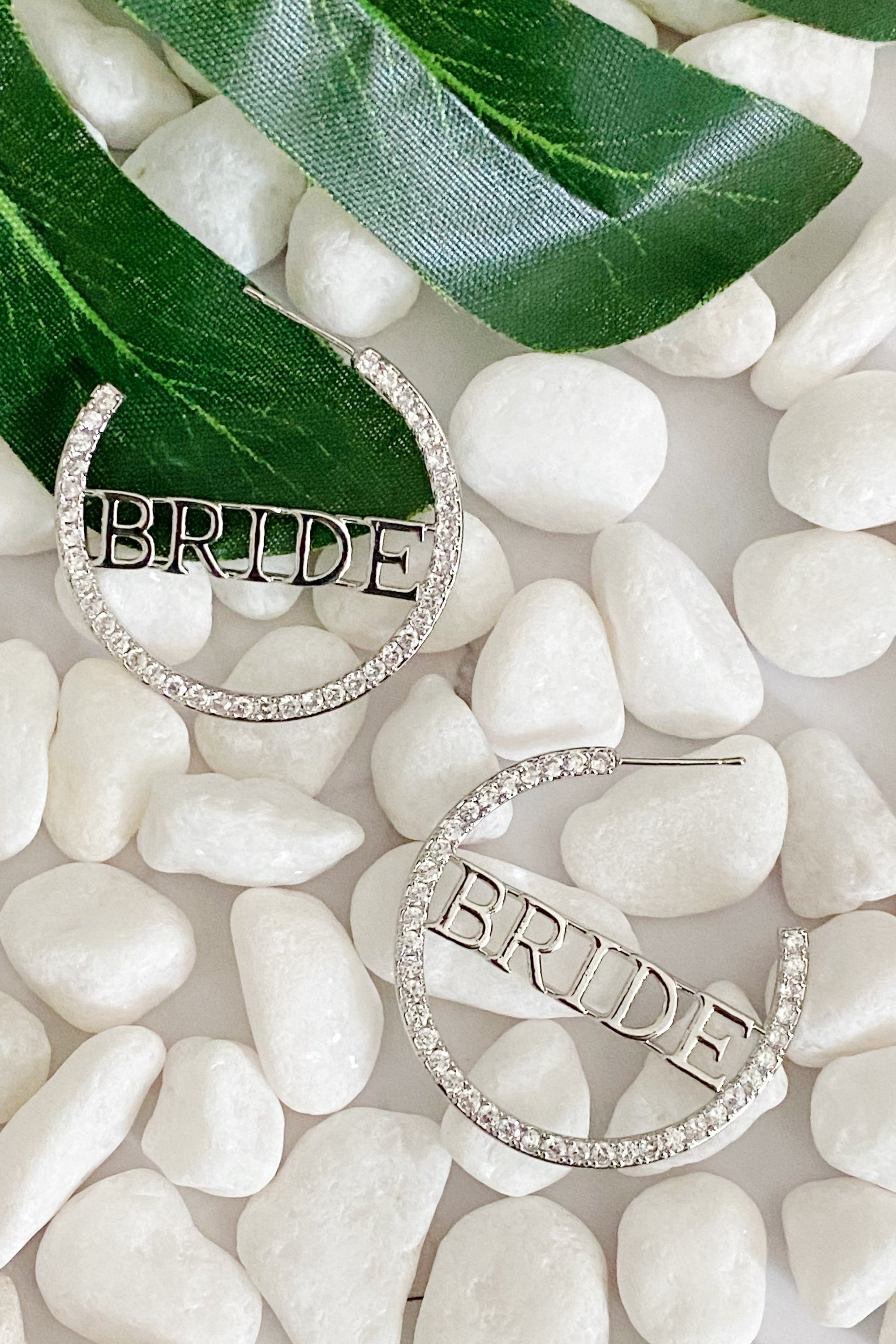 Elegant silver hoop earrings with 'BRIDE' engraving and sparkling accents, perfect for brides.